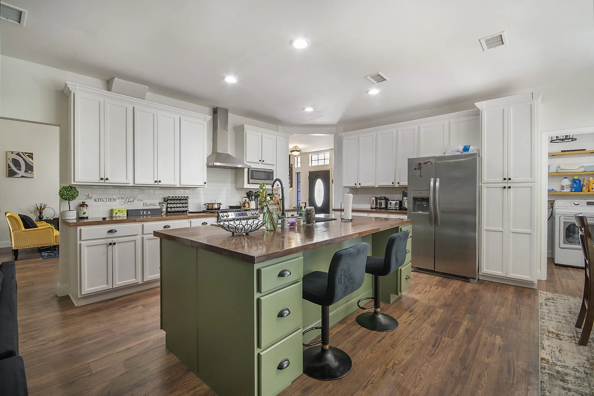 Kitchen island with seating, vent hood and stainless appliances.