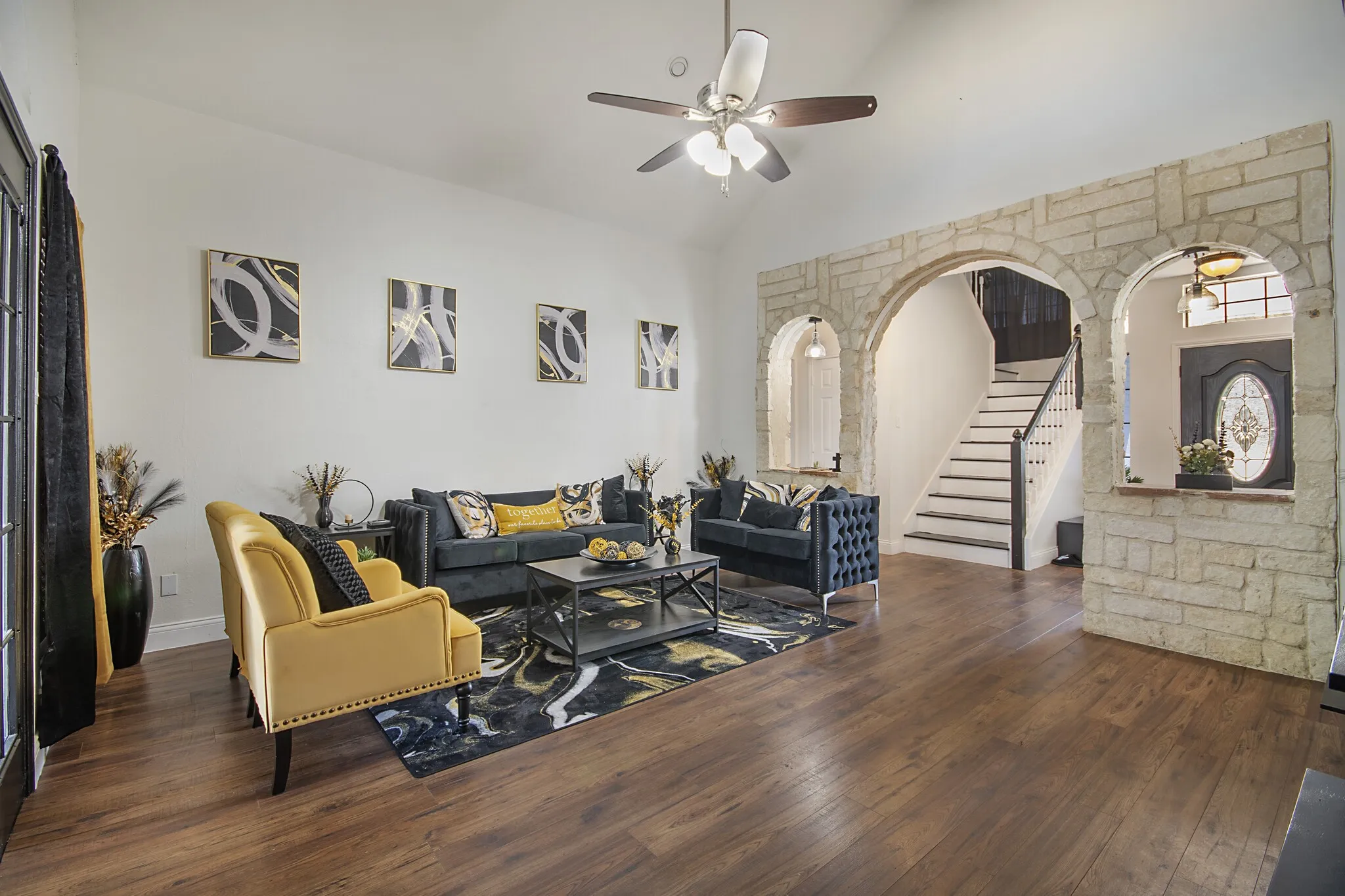 Formal living room framed by a stone archway, with wood-look flooring.