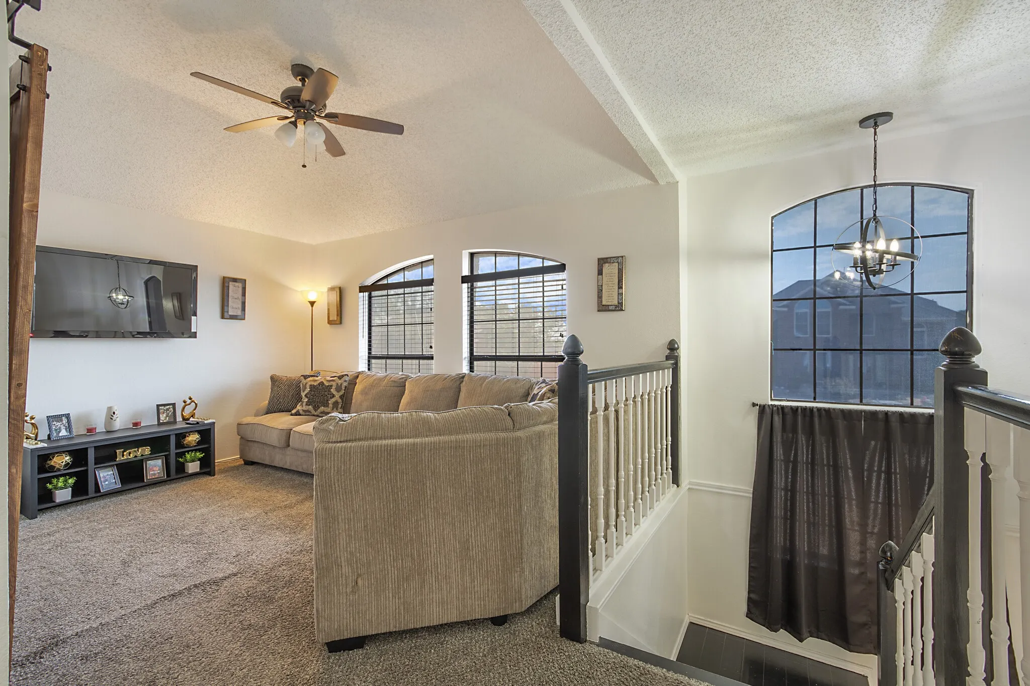 Upstairs loft overlooking the entry, with an arched window and iron railing.
