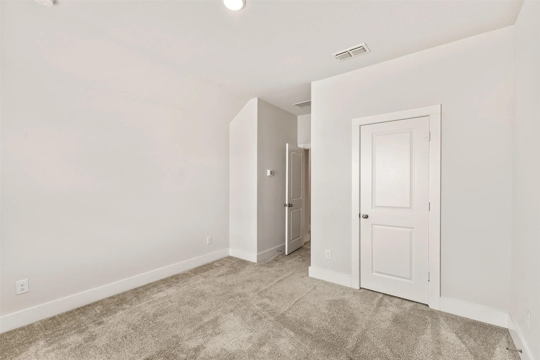 Plush carpet flooring, white painted walls, recessed ceiling lighting, and panel doors