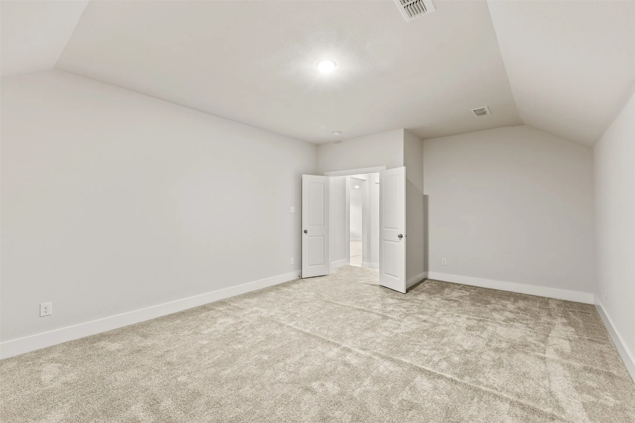 Carpeted room with a vaulted ceiling, recessed lighting, and a white paneled door