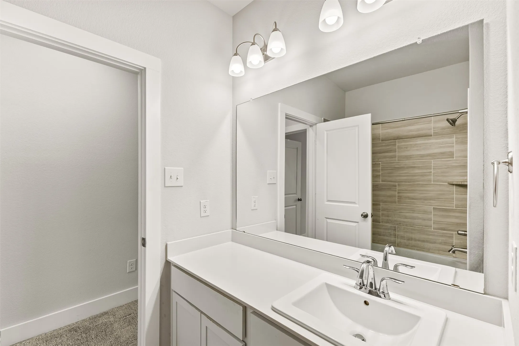 White vanity with an integrated rectangular sink, chrome faucet, and expansive wall-mounted mirror