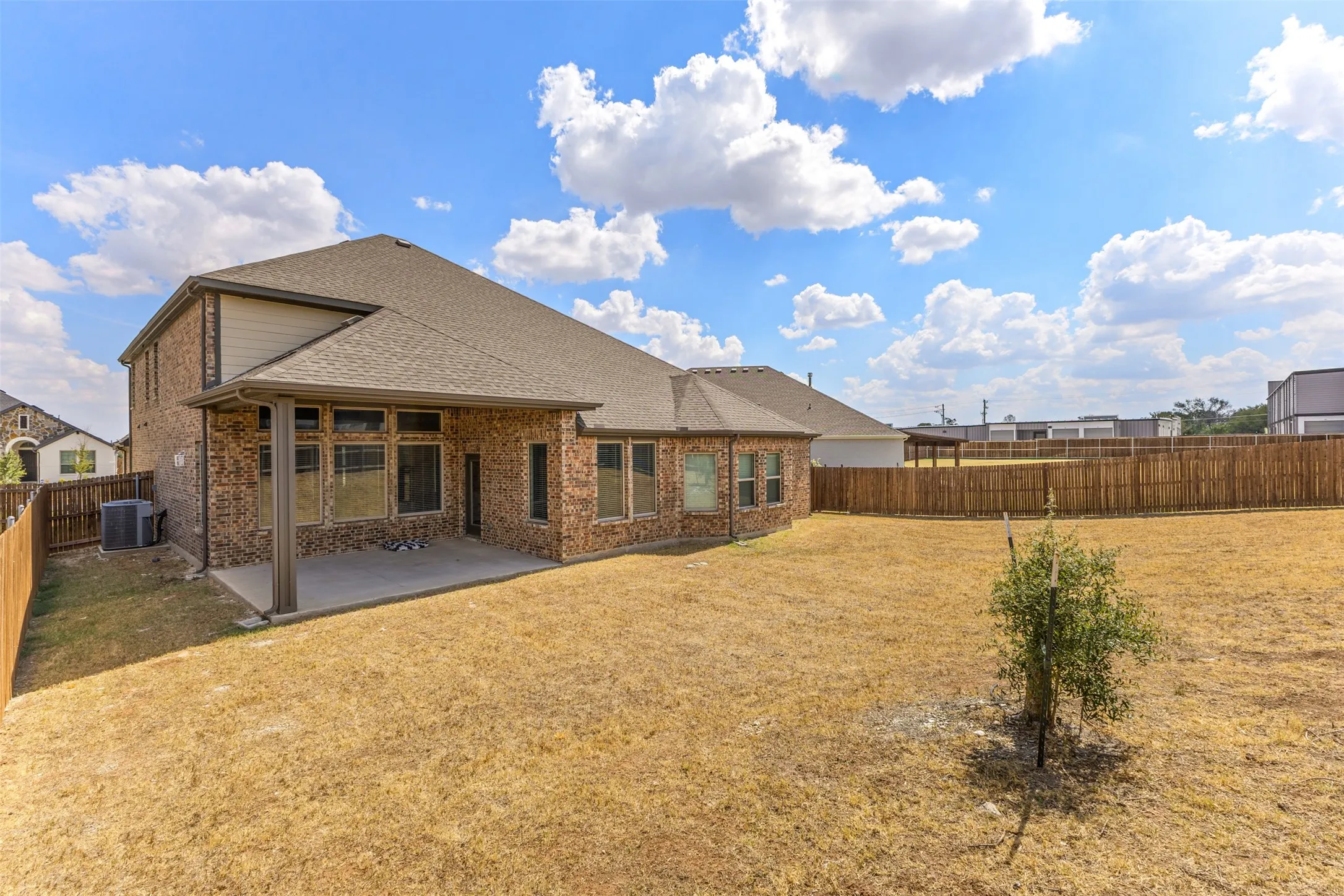Brick exterior with an extensive backyard, covered patio, multiple windows, and a complete privacy fence