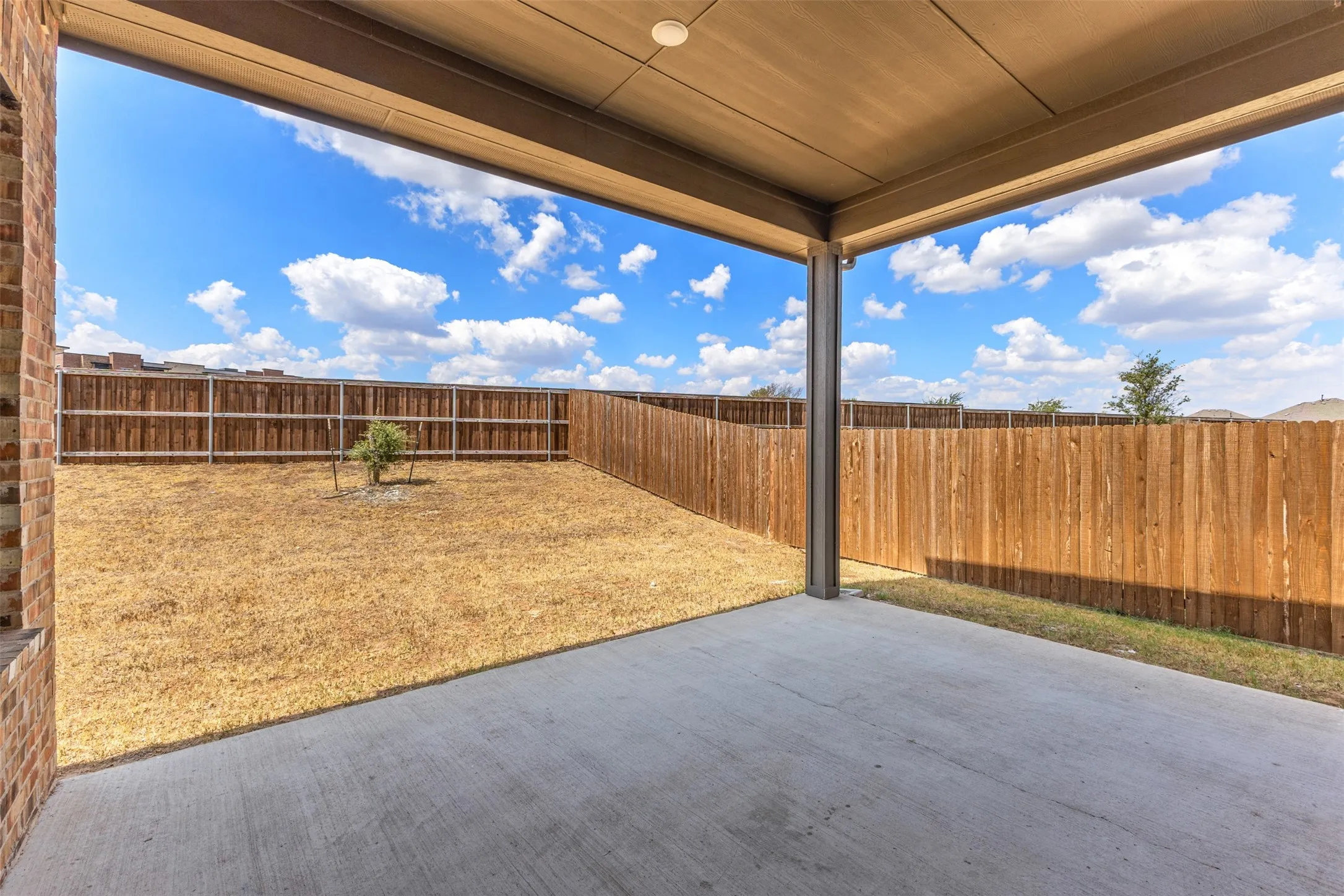 Covered concrete patio with a full privacy fence