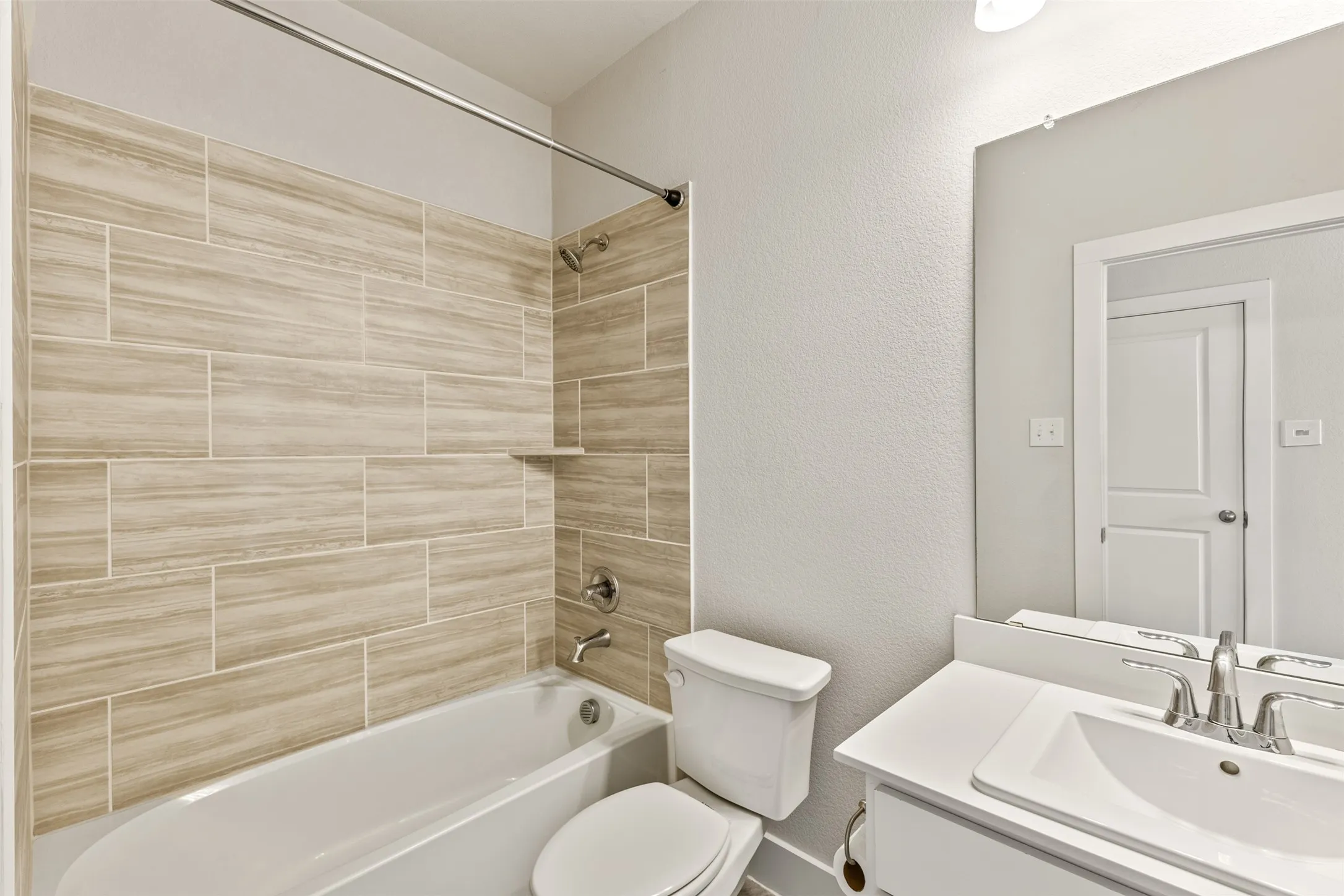 Bathtub with natural-toned rectangular tile surround and built-in niche