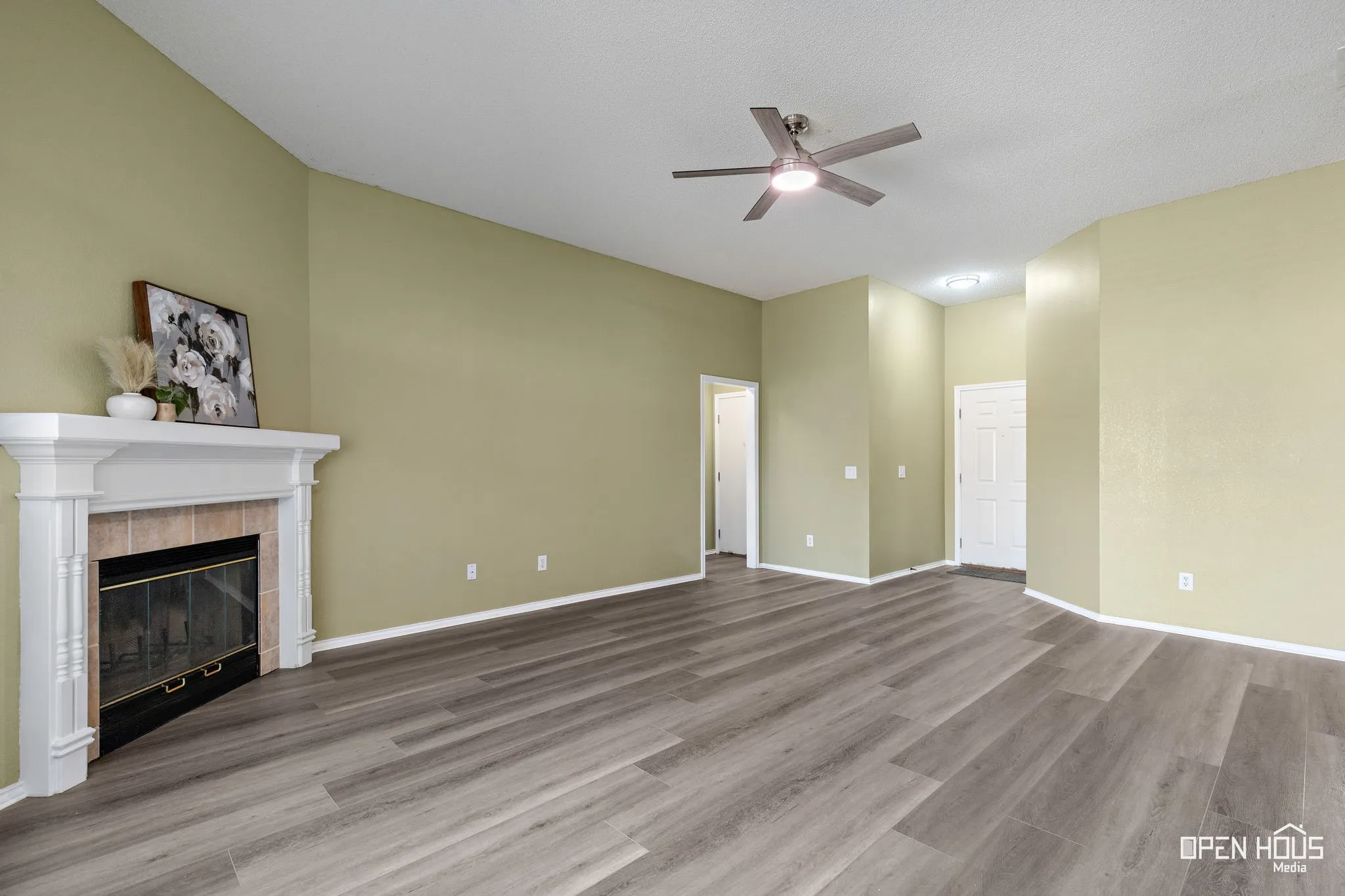 Wood-finish flooring throughout, va, built-in fireplace with tile surround and mantel, and ceiling fan with integrated lighting