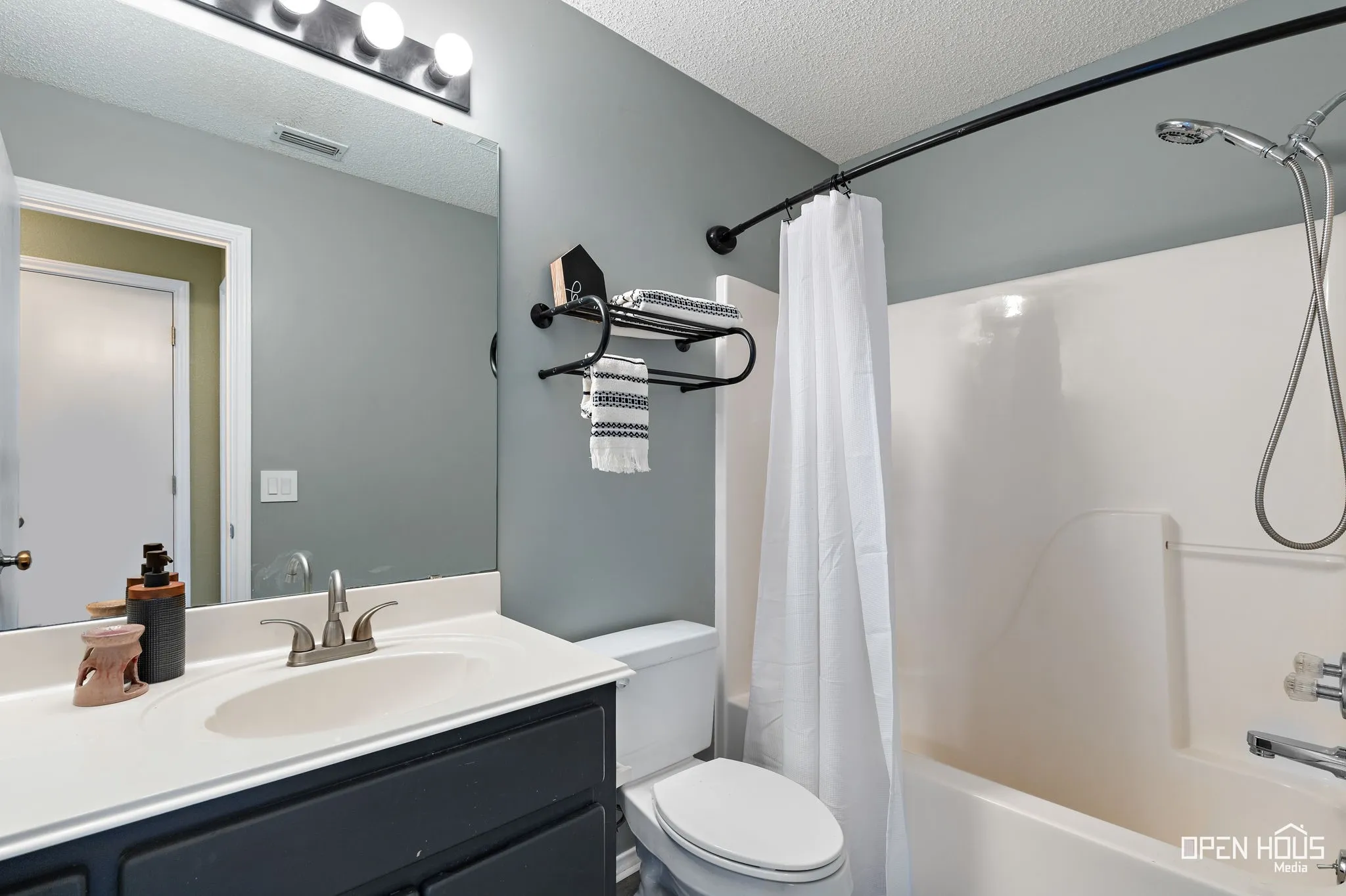 Bathroom featuring a vanity with an integrated sink, brushed nickel faucet, full-width mirror, and a shower/tub combination with a wall-mounted showerhead