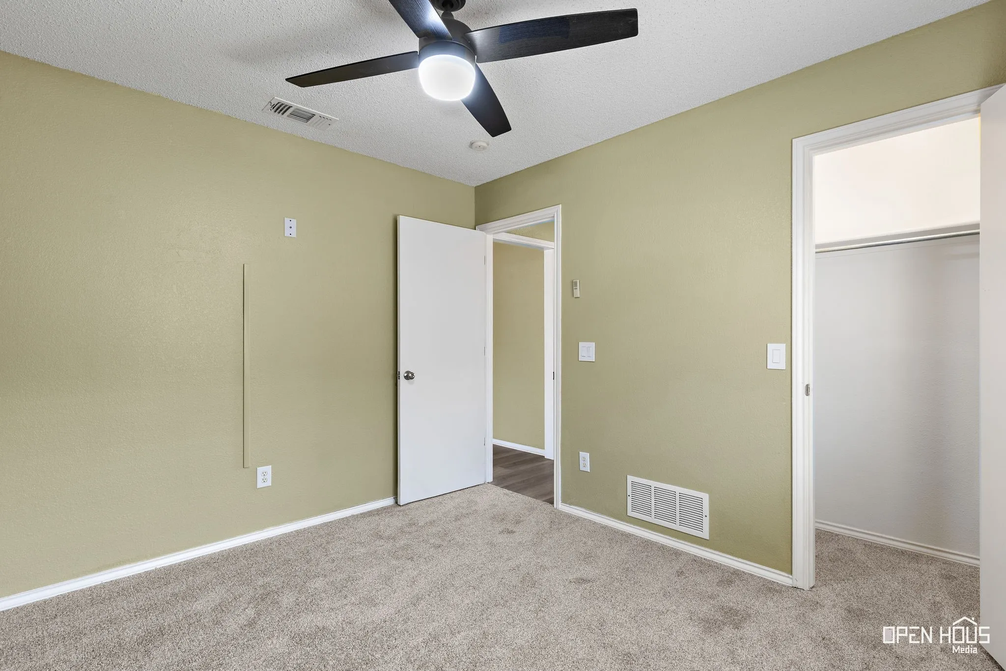 Recessed ceiling with an attached ceiling fan, neutral wall paint, and gray carpet flooring