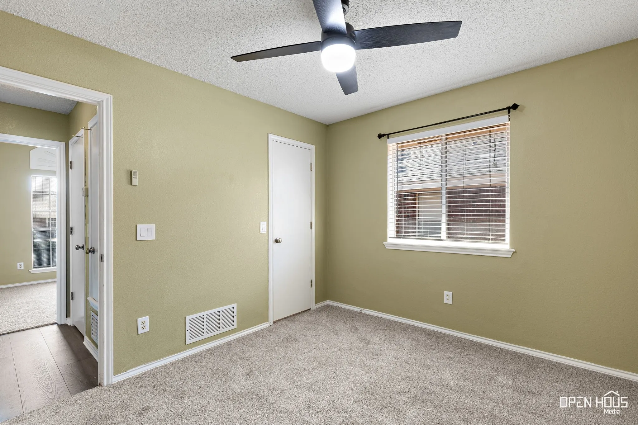 Carpeted room featuring a ceiling fan with integrated lighting, a window with blinds