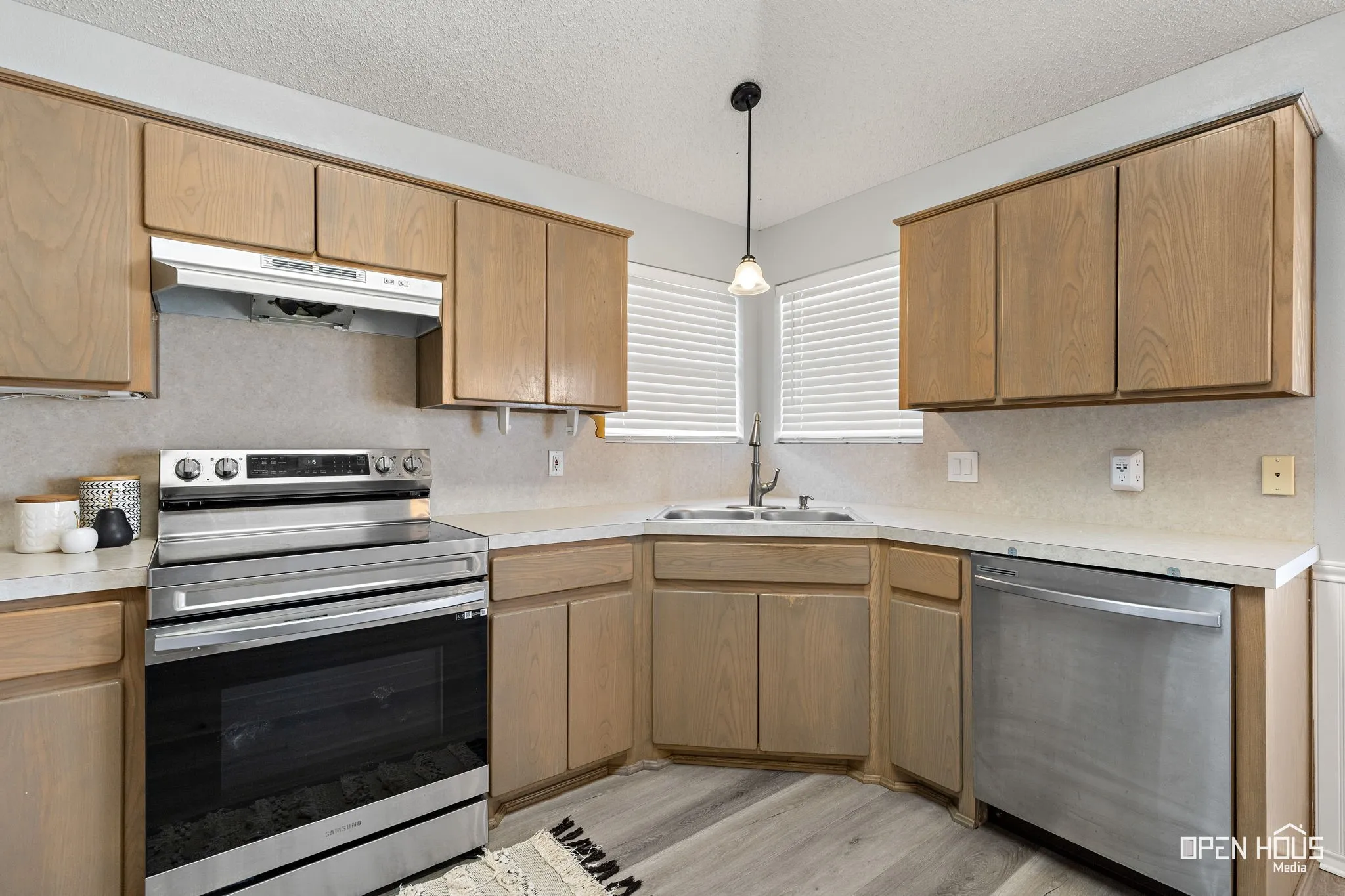 Kitchen with wood-finish cabinetry, light-toned countertops, and stainless steel appliances