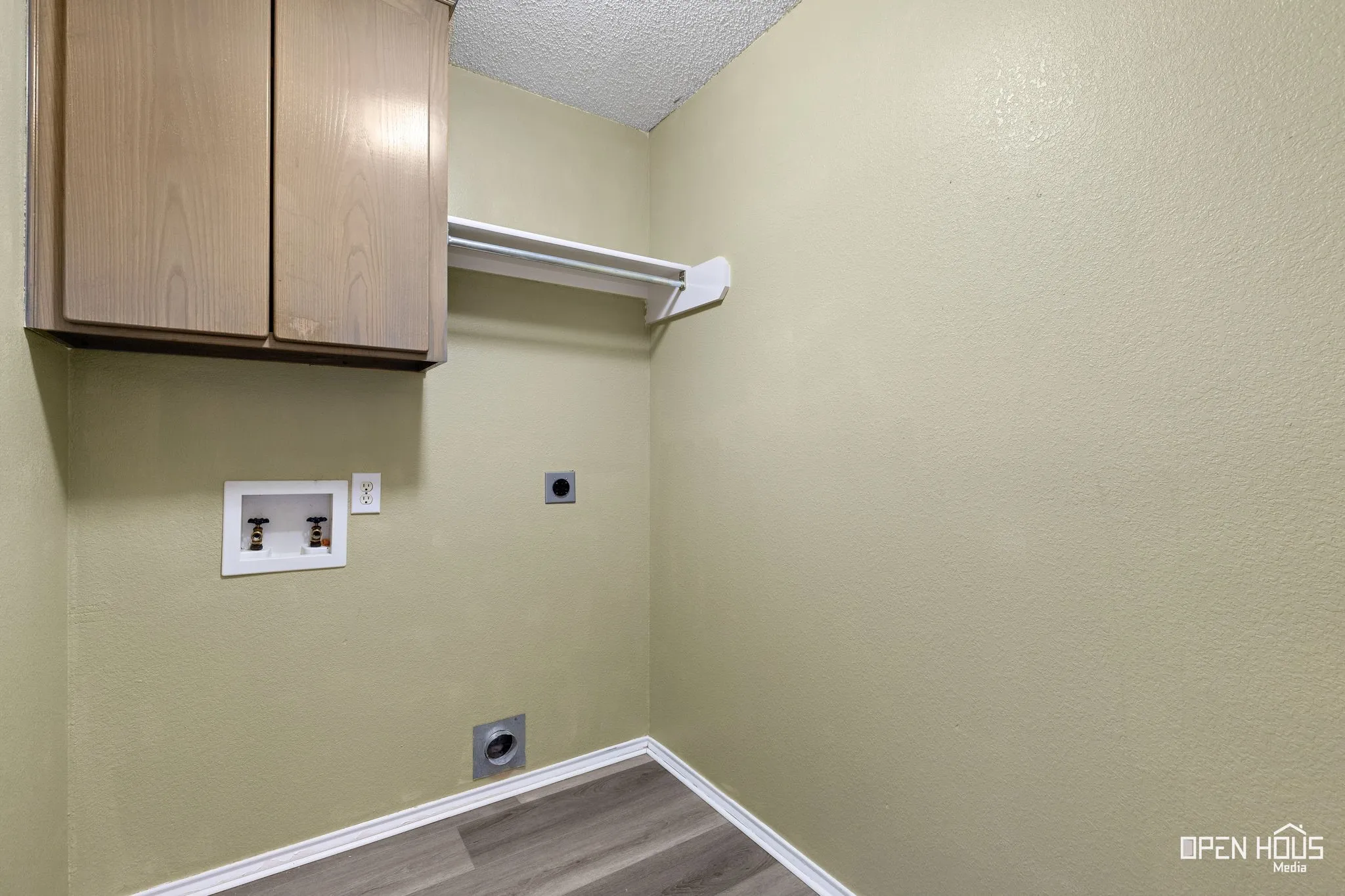 Updated flooring with white trim, upper cabinetry, and a hanging rod