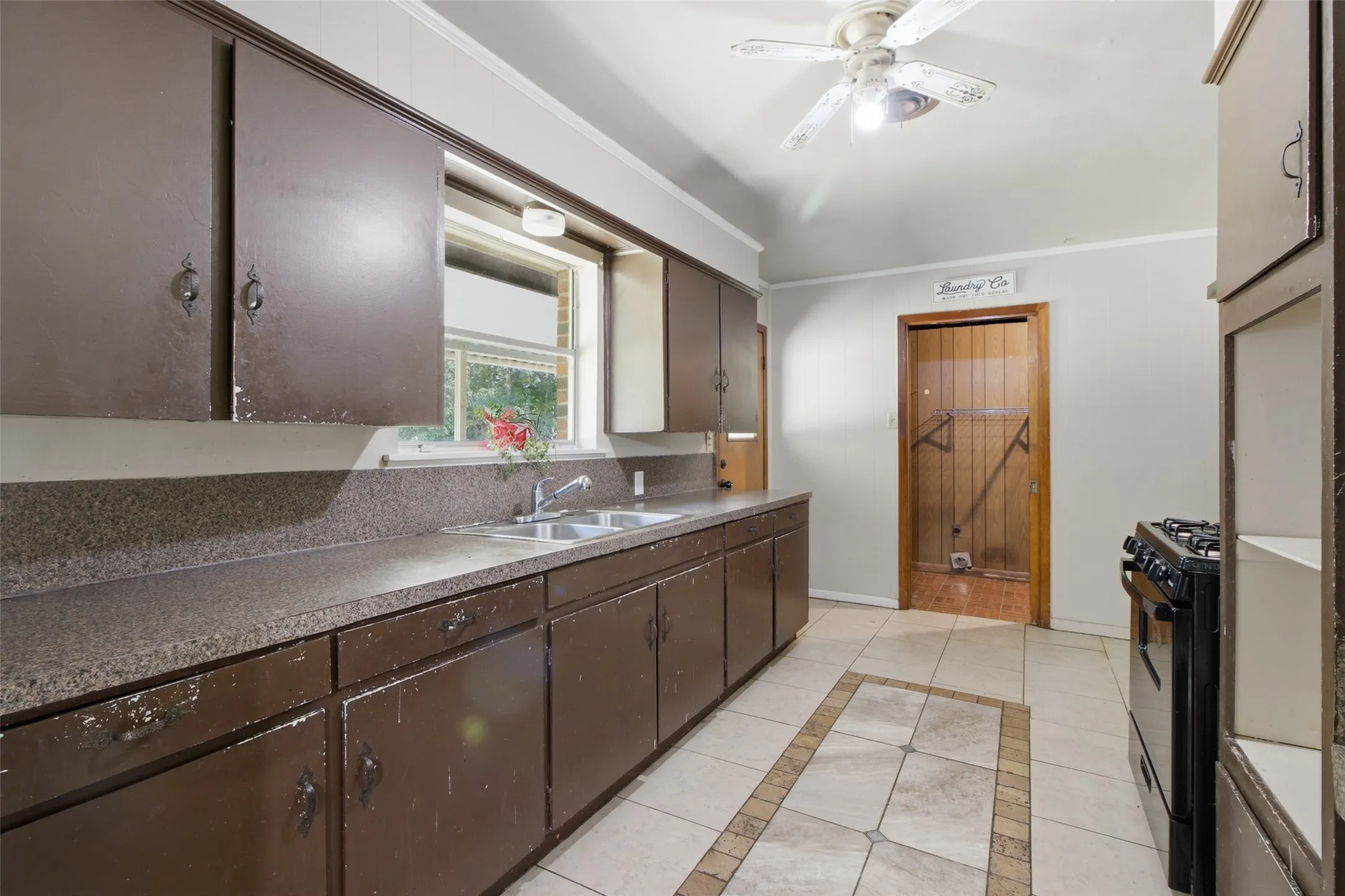 Kitchen featuring extensive cabinetry, a double basin stainless steel sink, and a gas range