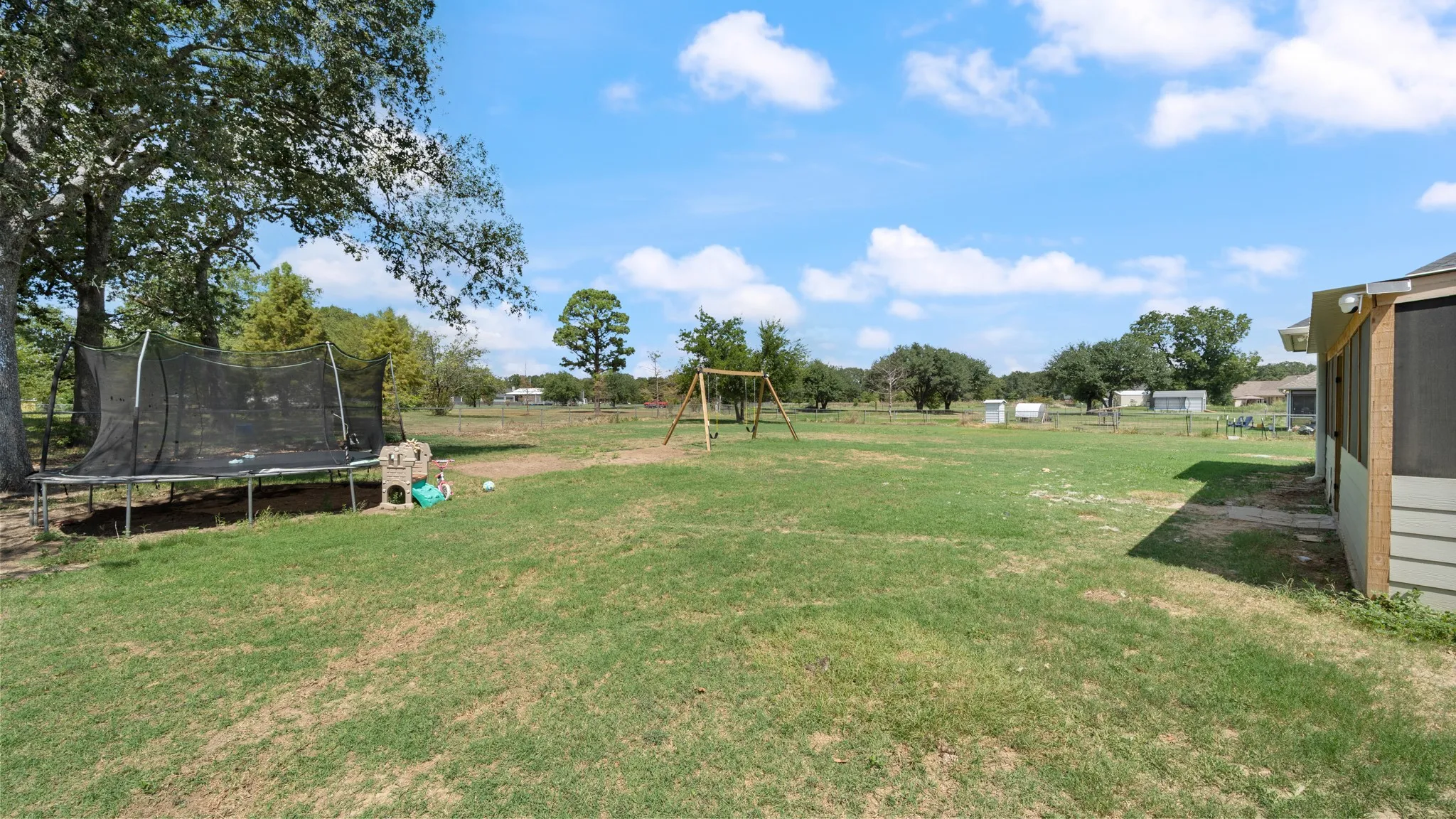 Expansive grassy yard with mature trees and a screened-in porch