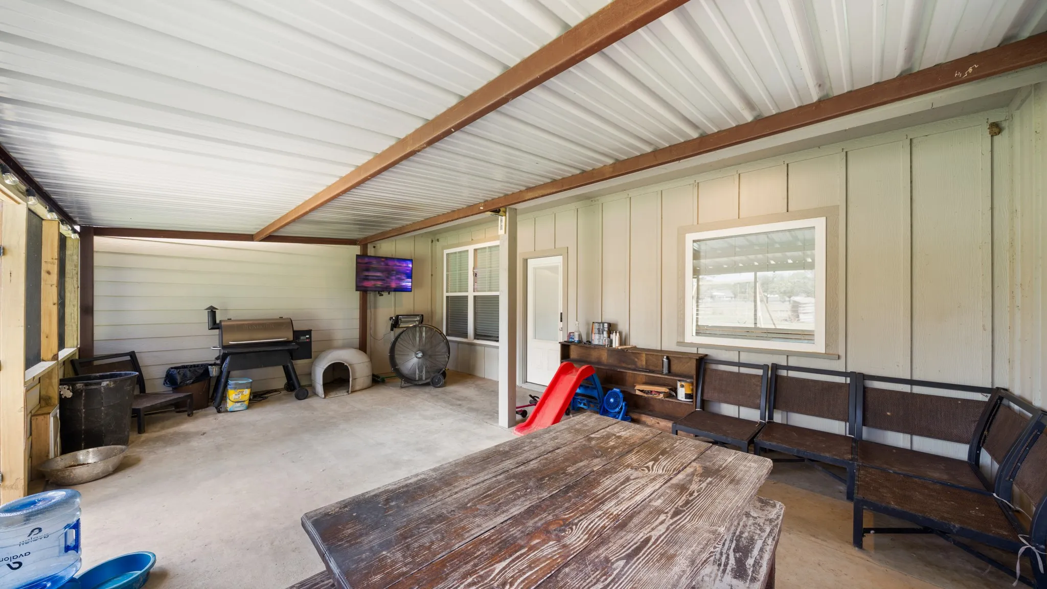 Covered back porch with a durable metal roof, concrete flooring, and horizontal siding