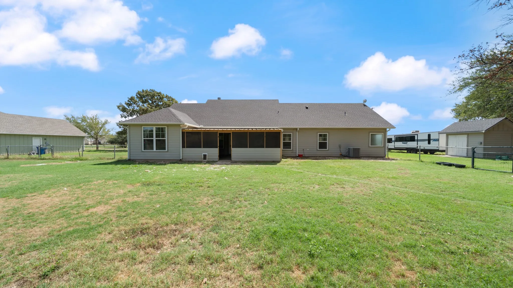 Expansive fenced backyard with a screened porch, an additional detached structure, and a secondary structure
