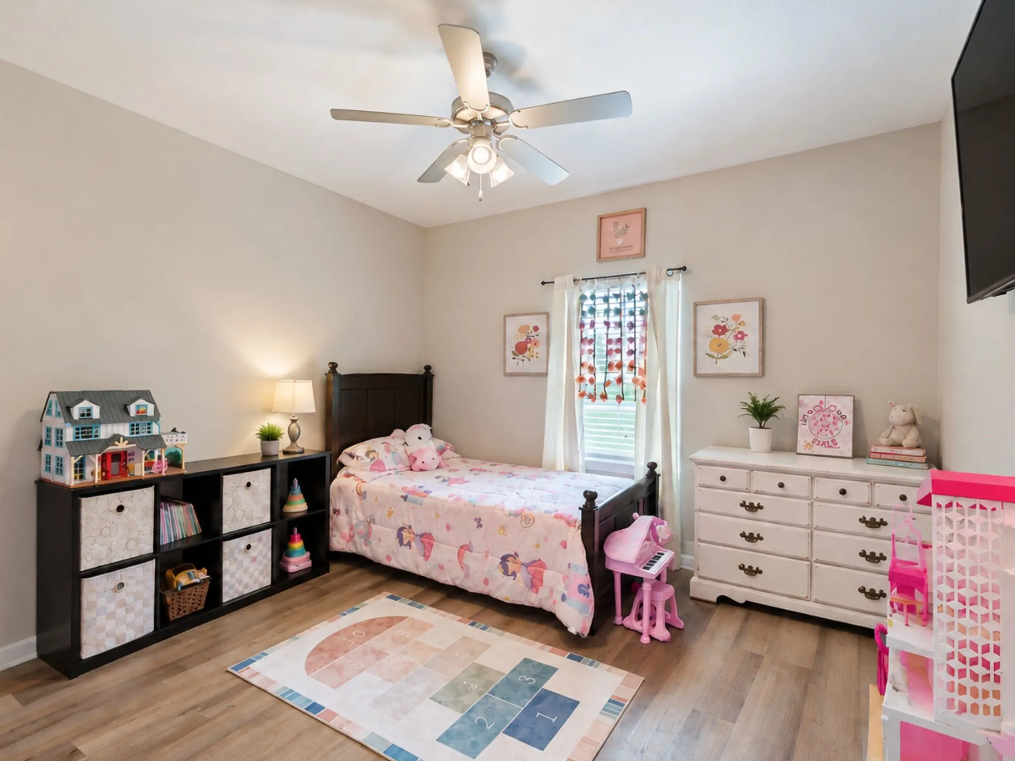 Wood-finish flooring, ceiling fan with integrated lighting, window with white trim, and light-toned walls