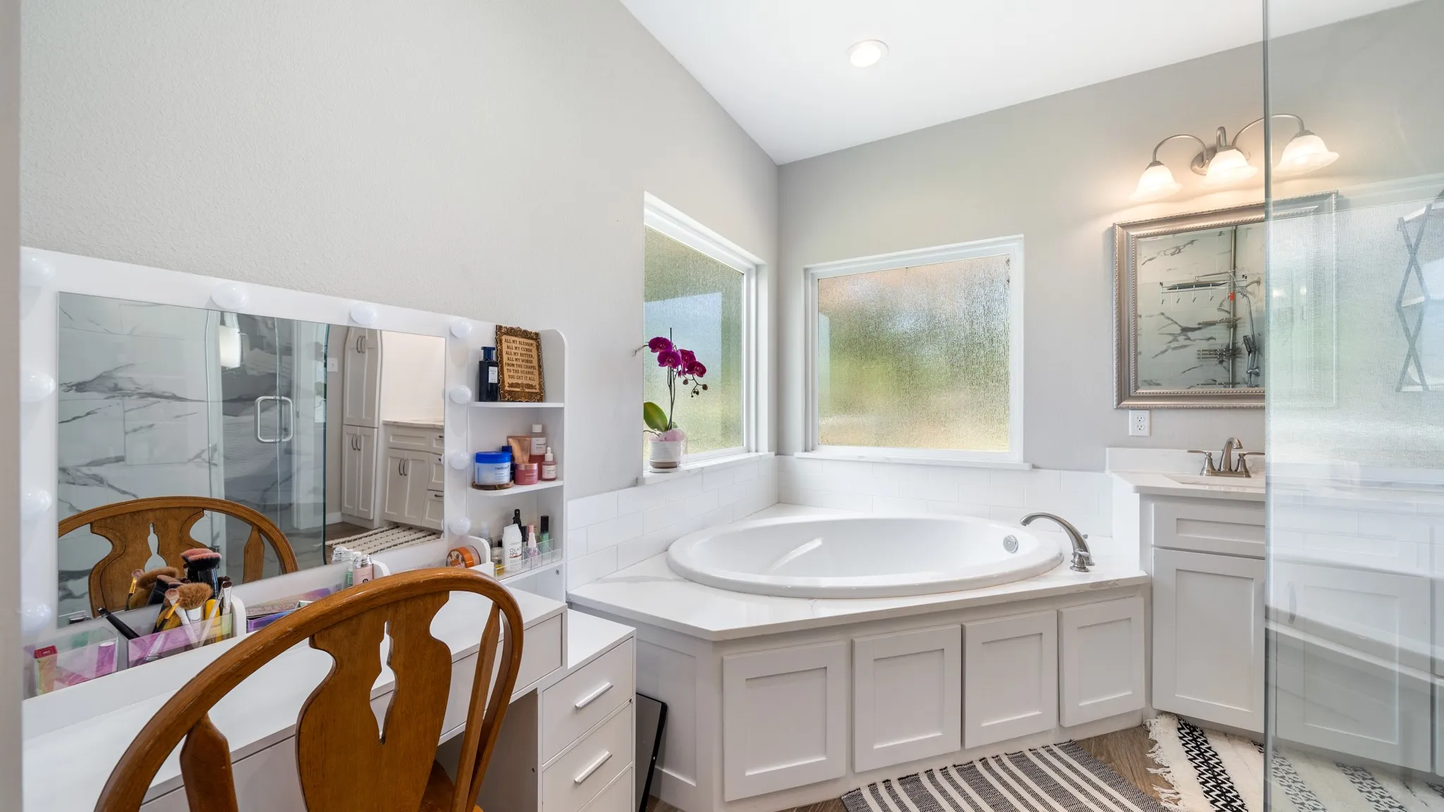 Built-in corner tub with surrounding countertop, dual windows, and single vanity with an integrated sink