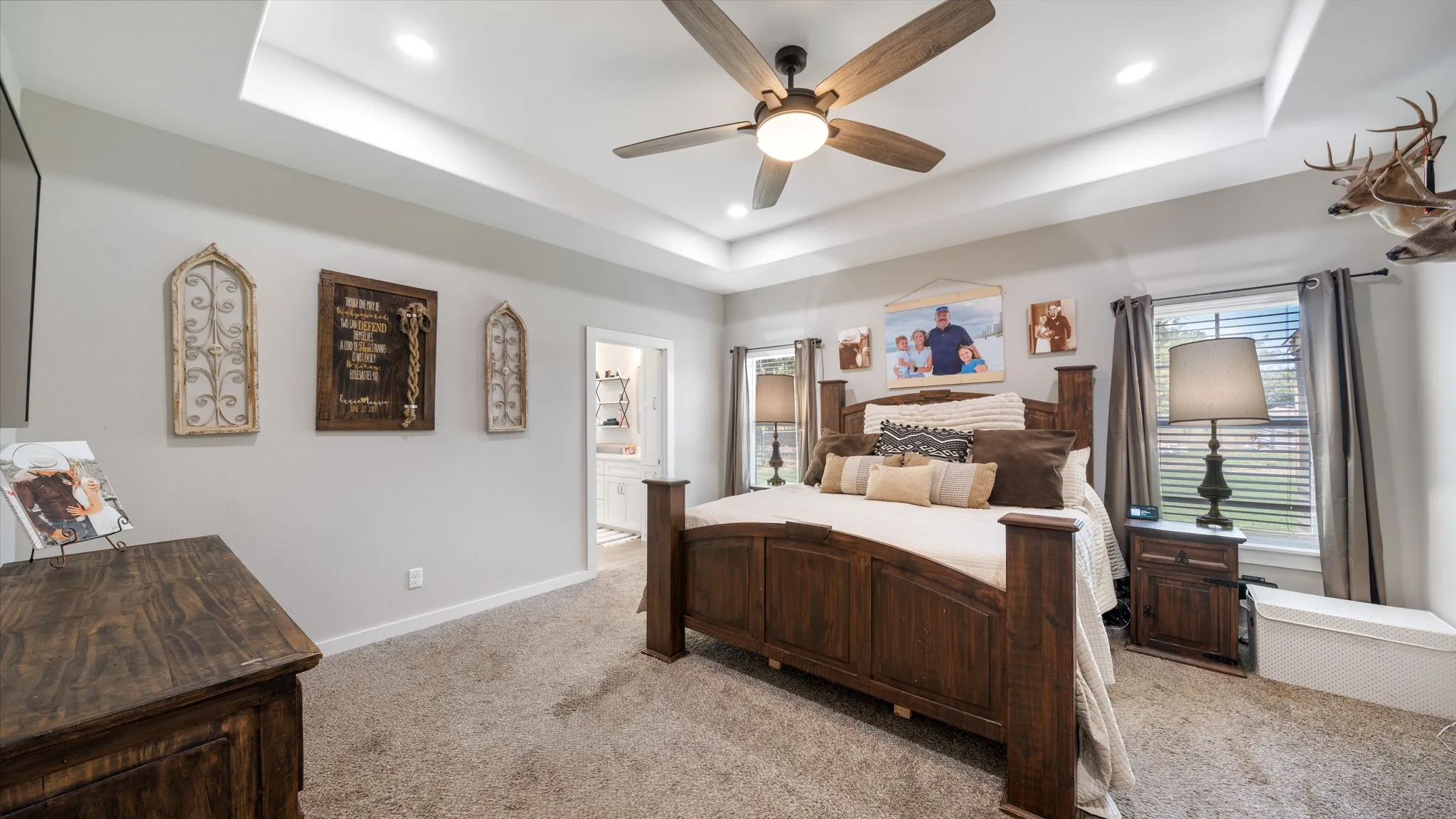 Tray ceiling with recessed lighting, ceiling fan with integrated light, light gray wall paint, and carpeted flooring
