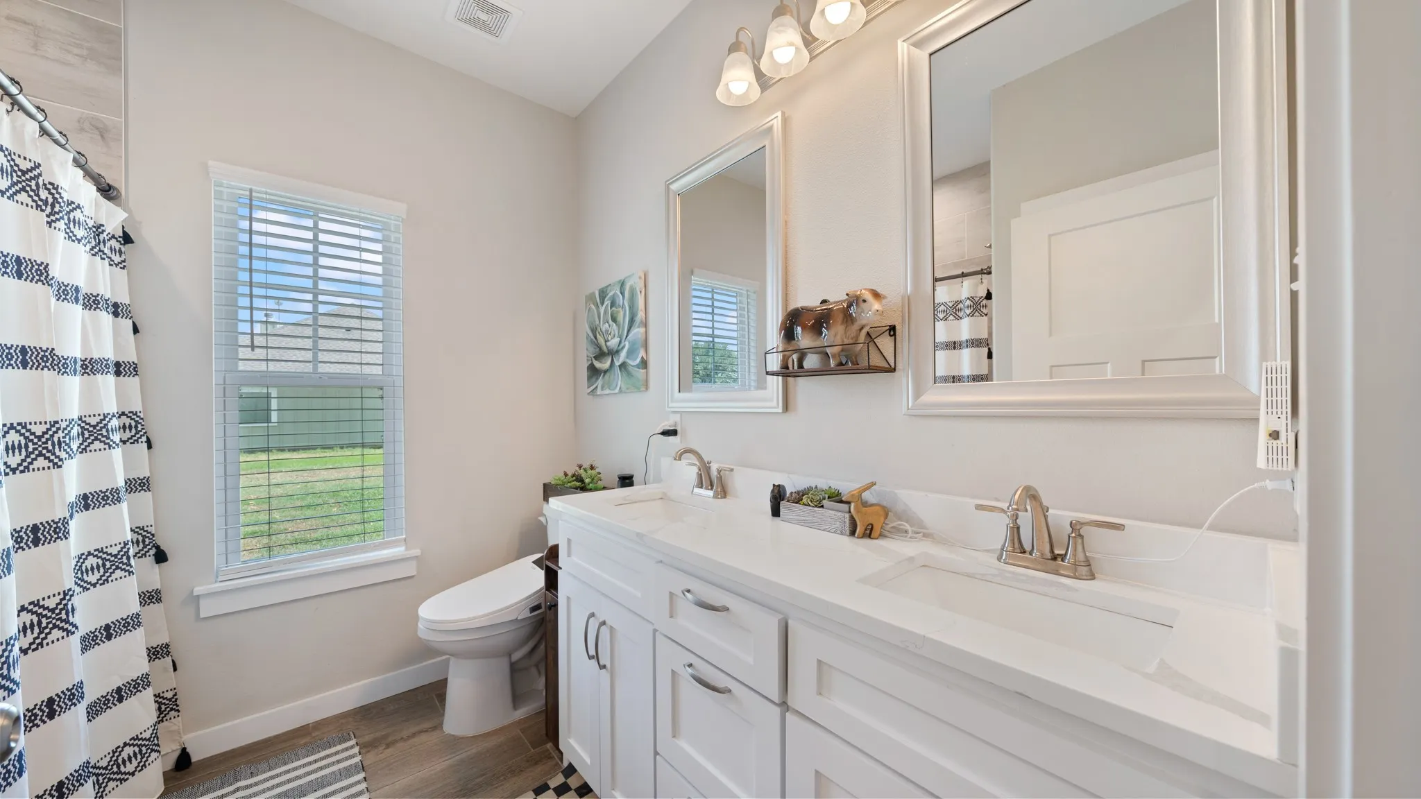 Dual vanity with integrated sinks, brushed nickel fixtures, two framed mirrors, and overhead lighting