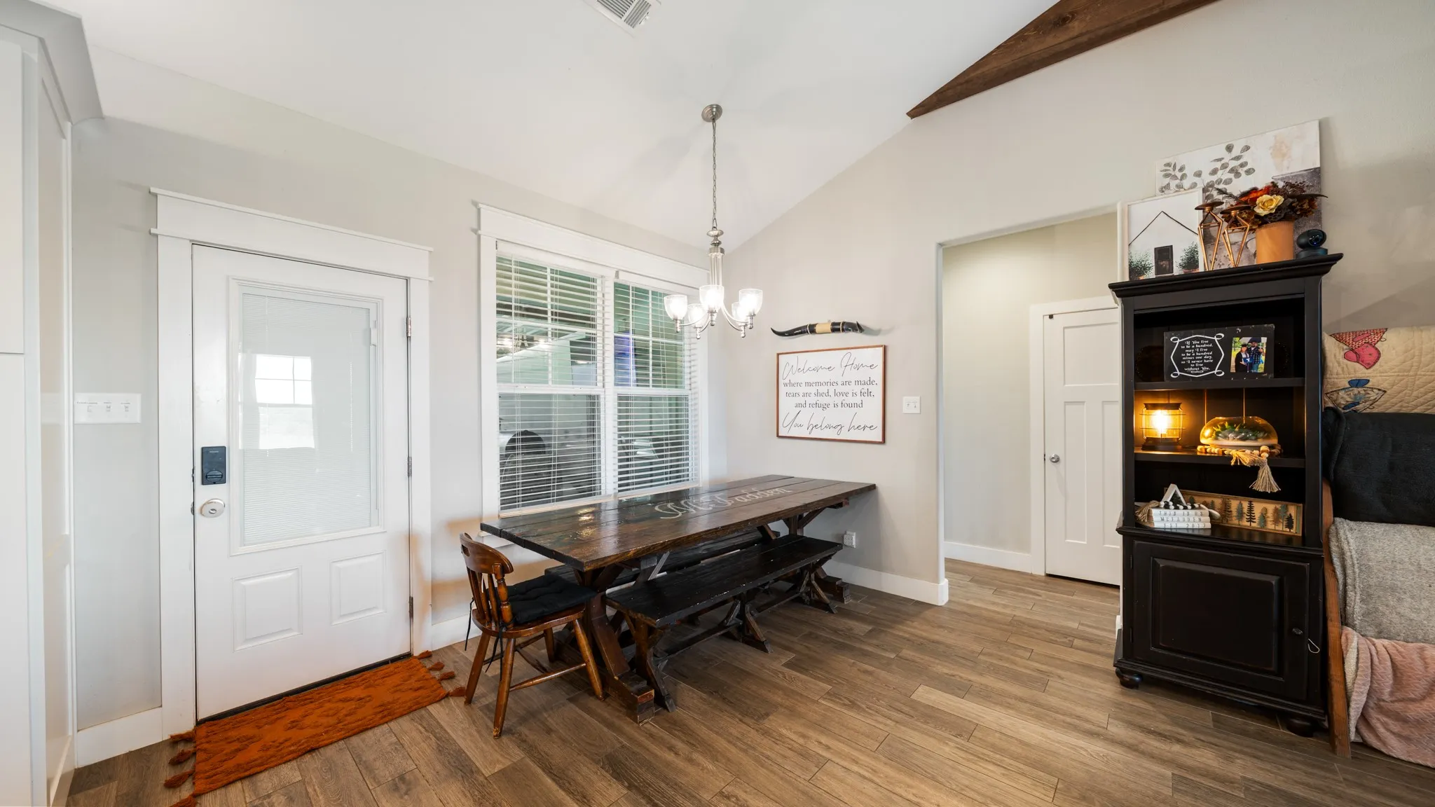 Vaulted ceiling with exposed wood beam, wood-finish flooring, glass-paneled exterior door, and interior paneled door