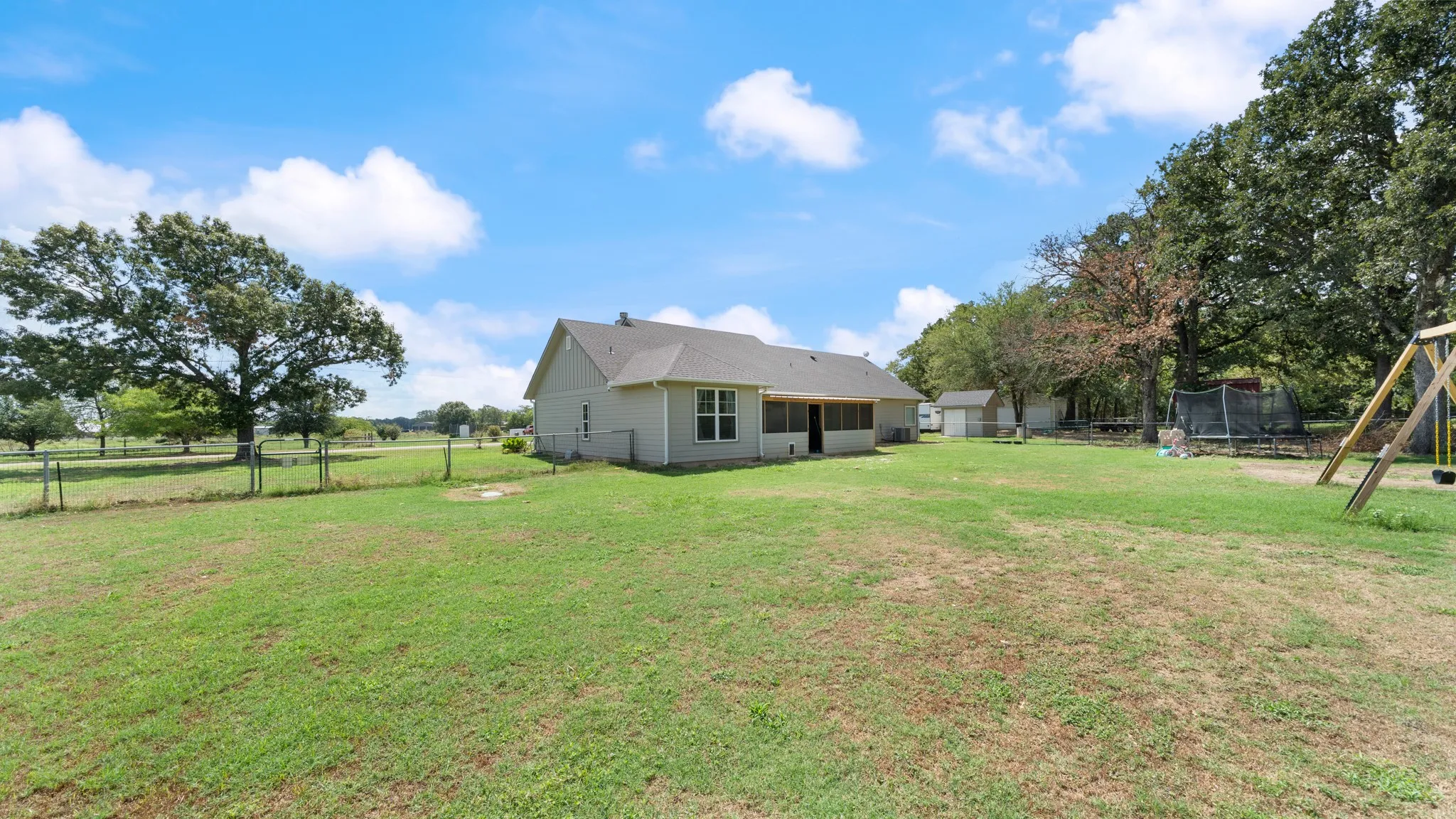 Expansive grassy area with mature trees and a detached shed