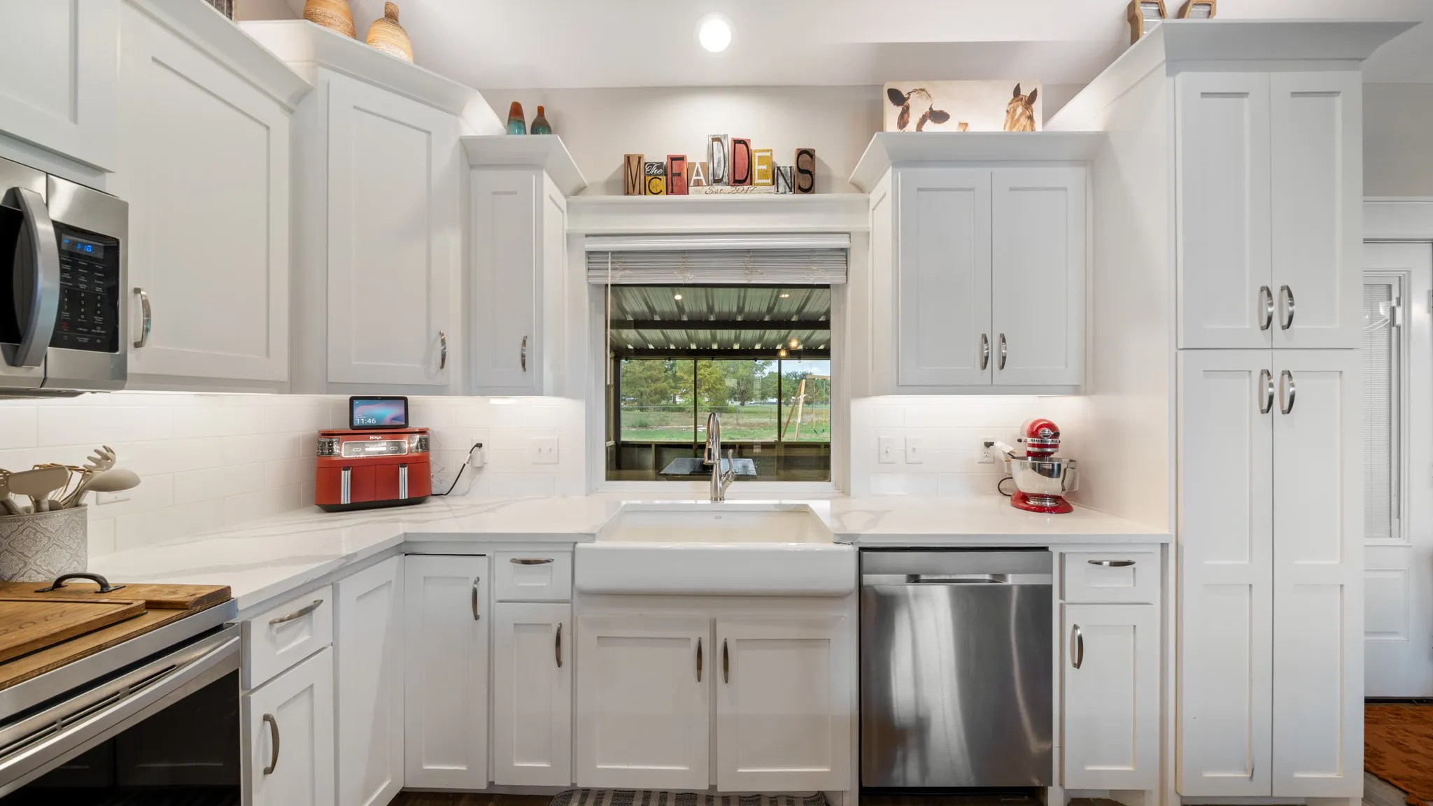 White shaker-style cabinetry, stainless steel appliances, undermount sink, solid surface countertops, and a subway tile backsplash