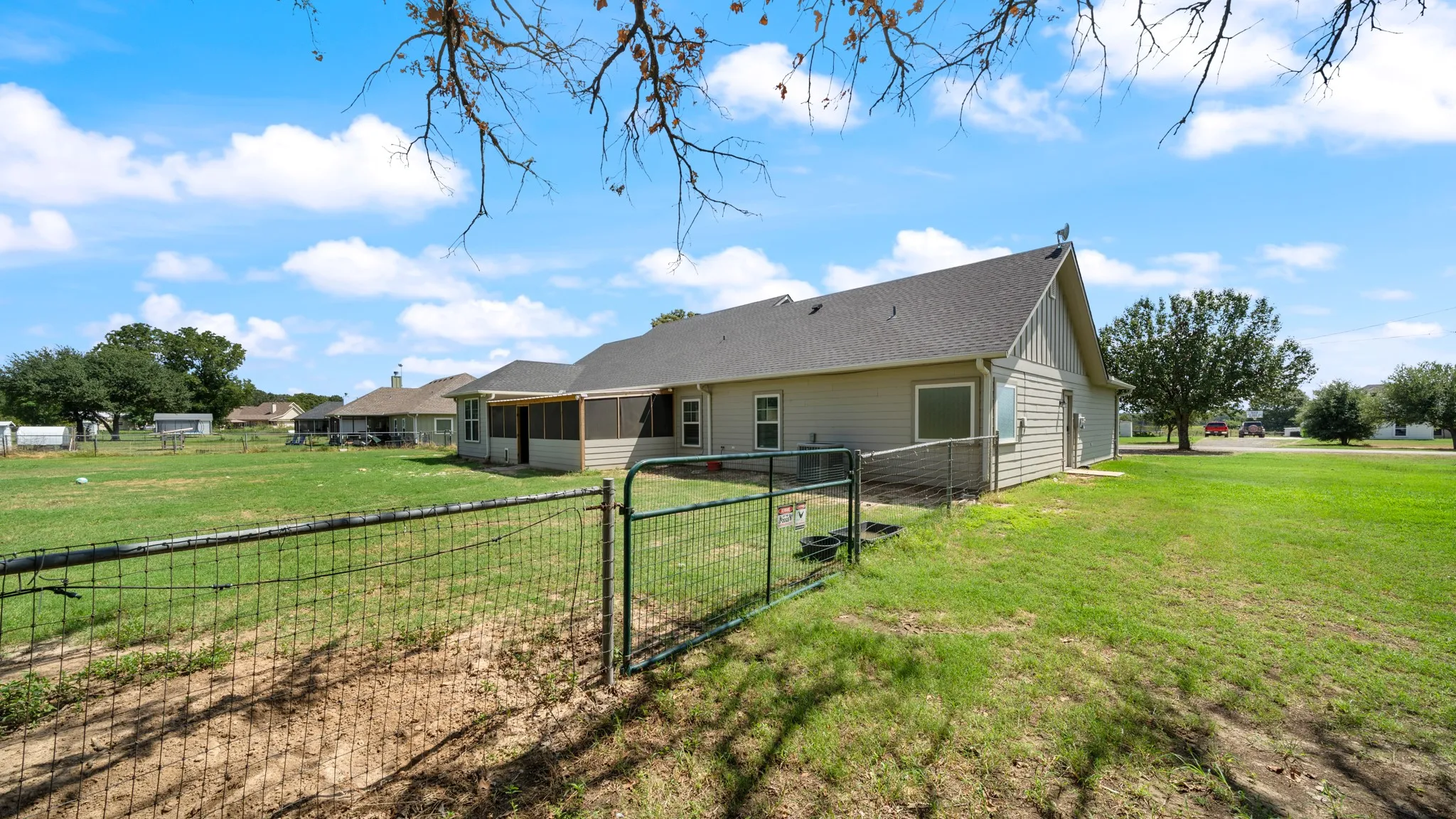Expansive grassy yard with a chain link fence and a screened-in porch