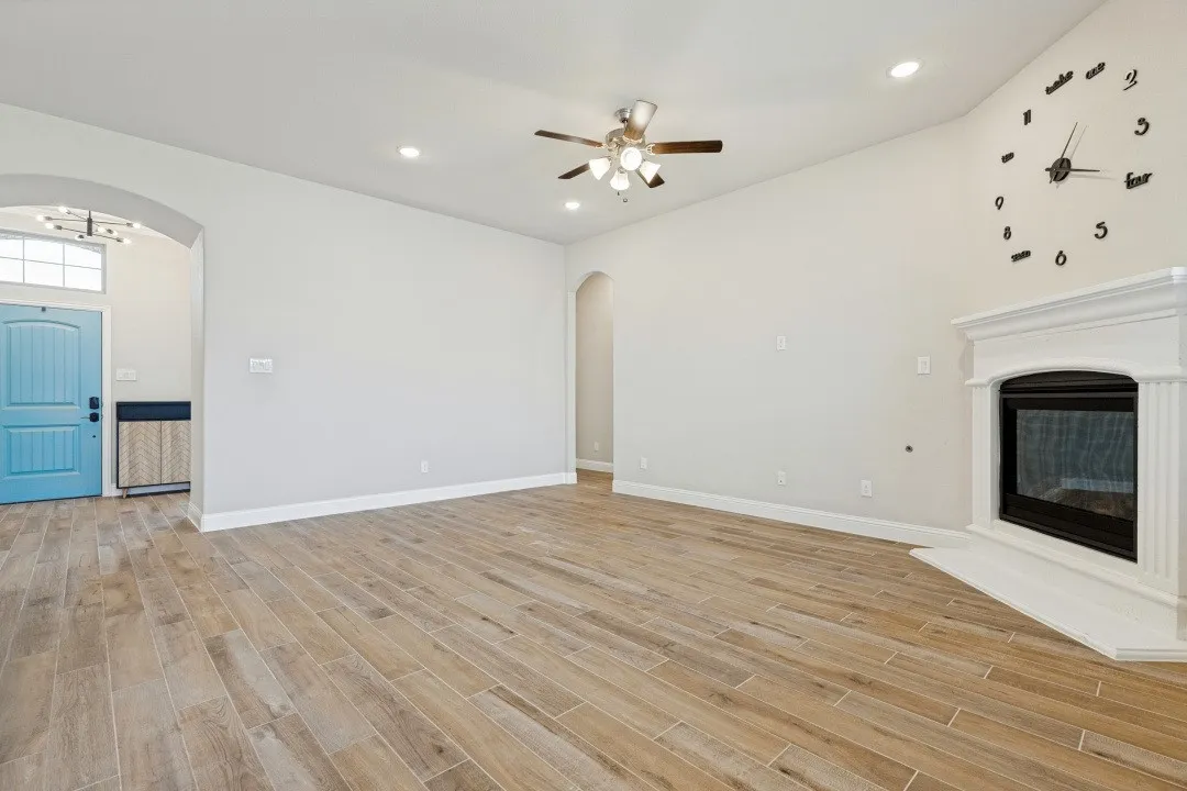 Living area featuring wood-finish flooring, vaulted ceiling, recessed lighting, and a built-in fireplace with a white mantel