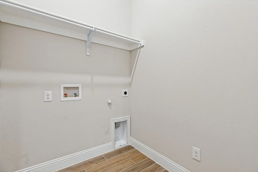 Laundry area featuring wood-look tile flooring, white shelving, and appliance hookups