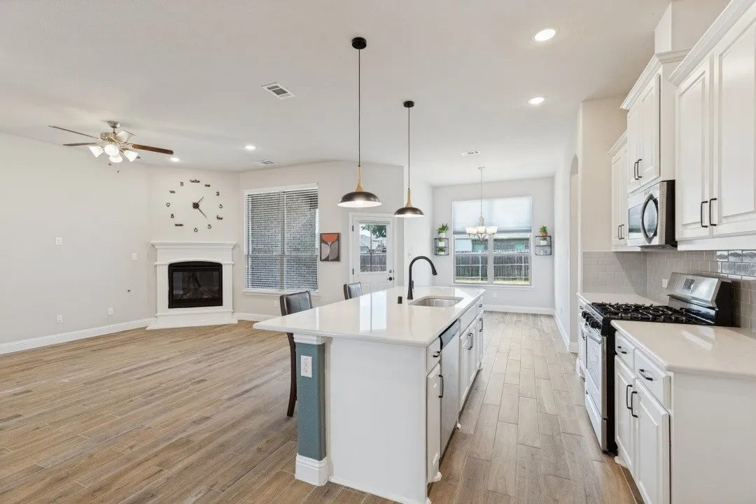 Gourmet kitchen with white cabinetry, stainless steel appliances, and a central island with a sink