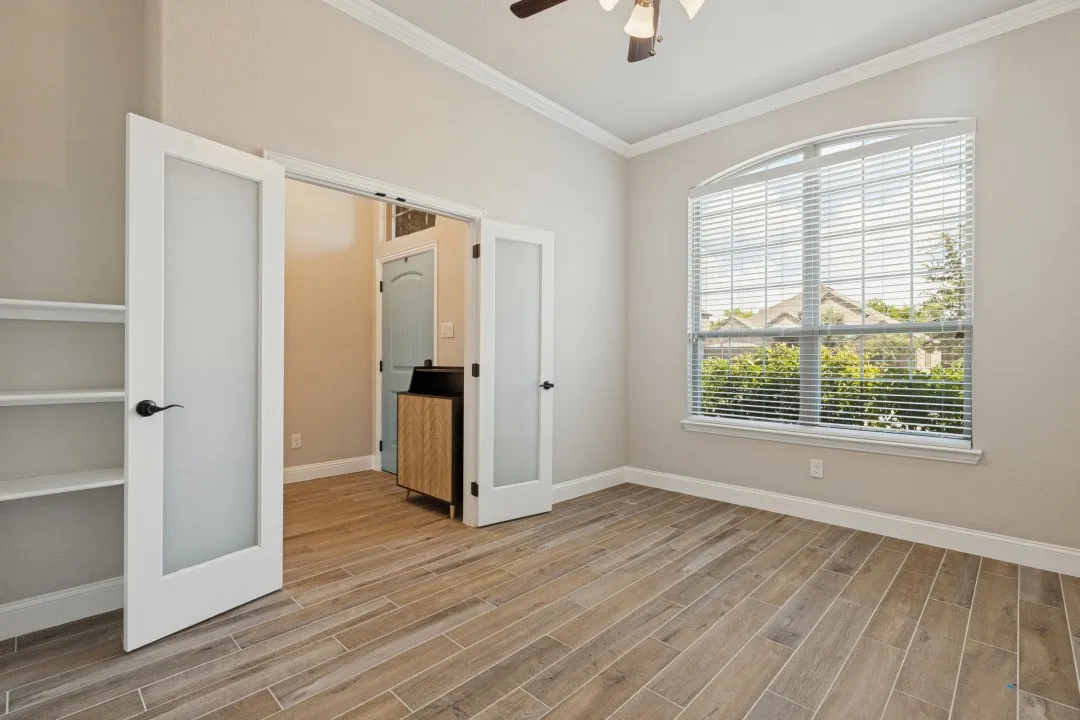 Oversize study with frosted glass panels, a ceiling fan, and cove molding makes it much easier to work. Plus storage
