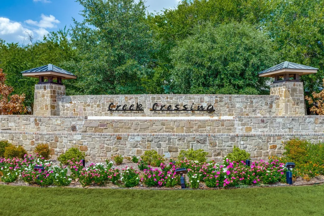 Stone entry monument with integrated architectural lighting and manicured landscaping