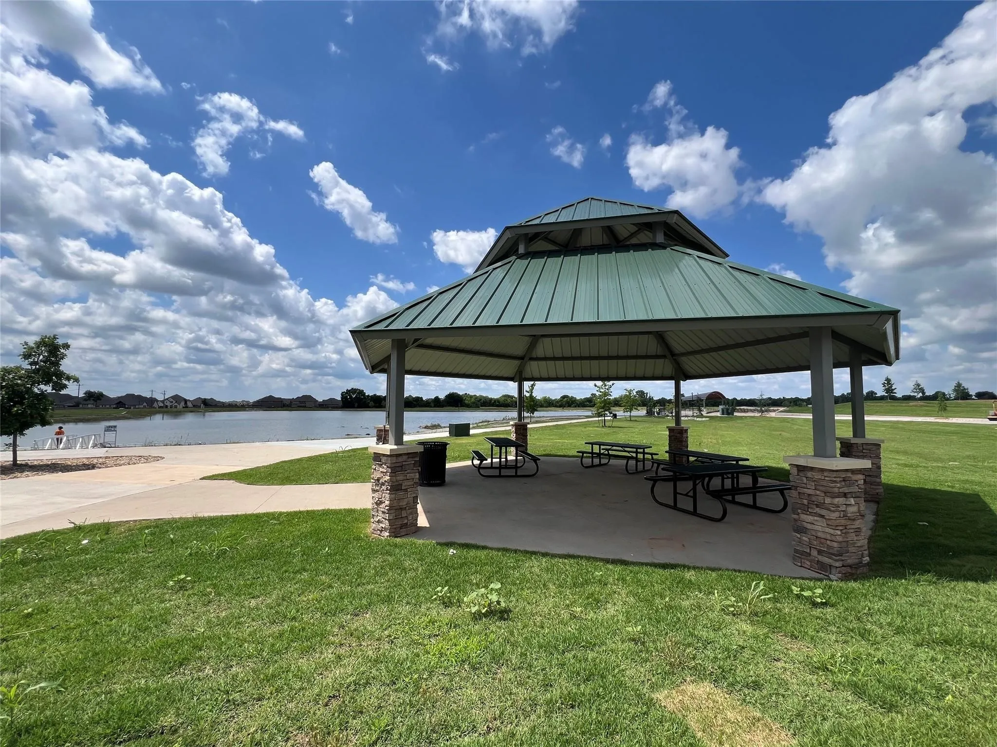Lakeside gazebo featuring a multi-tiered metal roof and stone-clad support columns