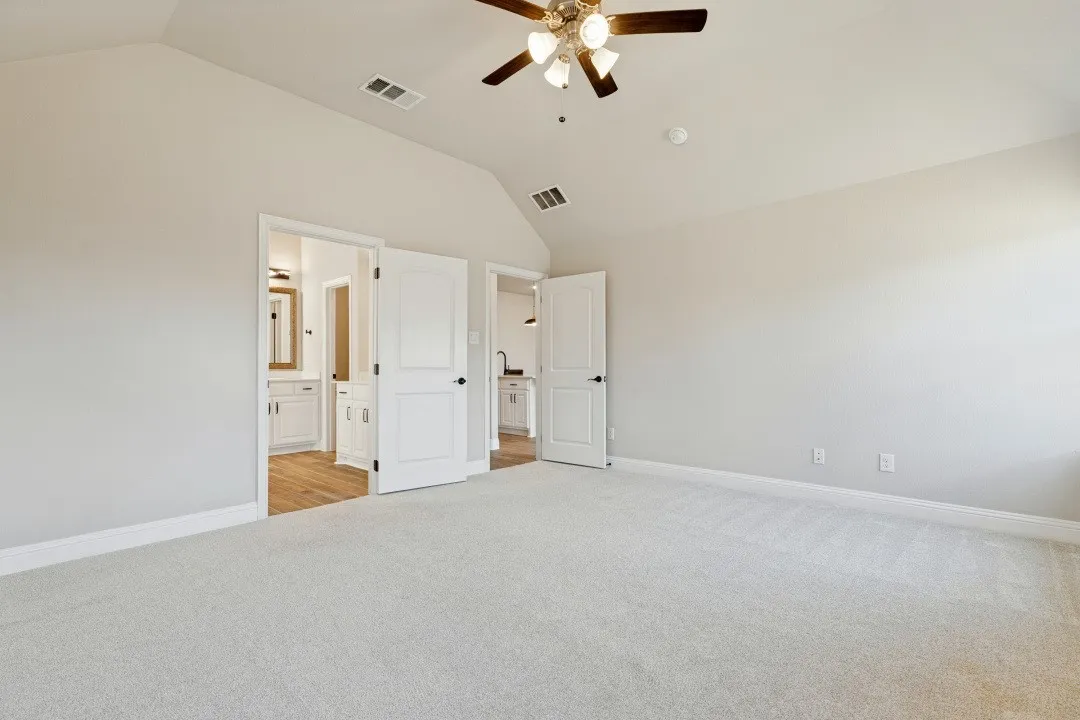 Vaulted ceiling with a ceiling fan, light-toned carpeting, white walls, and white trim