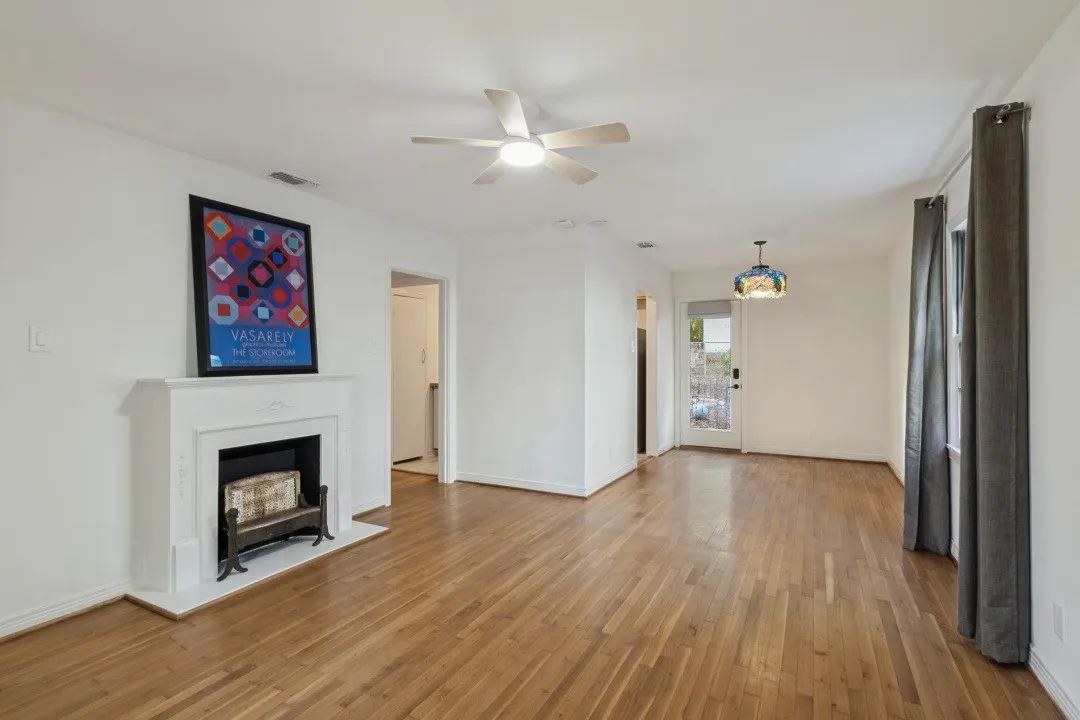 Hardwood flooring, white fireplace with mantle, ceiling fan, recessed lighting, and a glass-paneled door