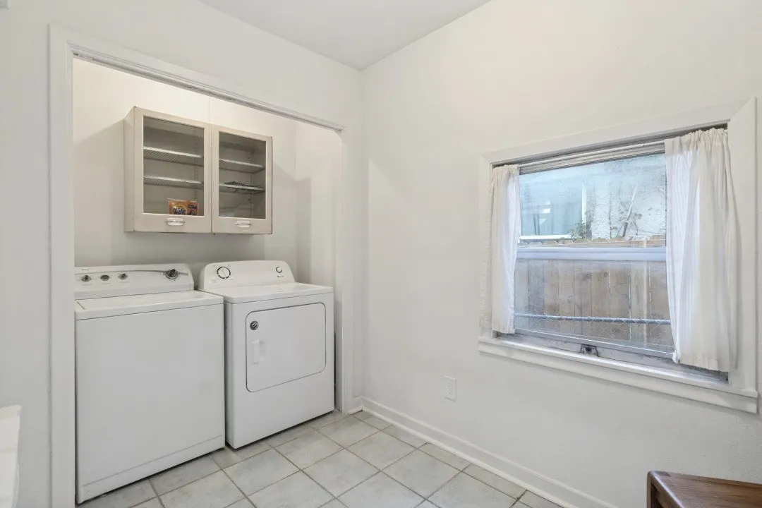 Tile flooring, built-in upper cabinetry with glass inserts, and an exterior-facing window