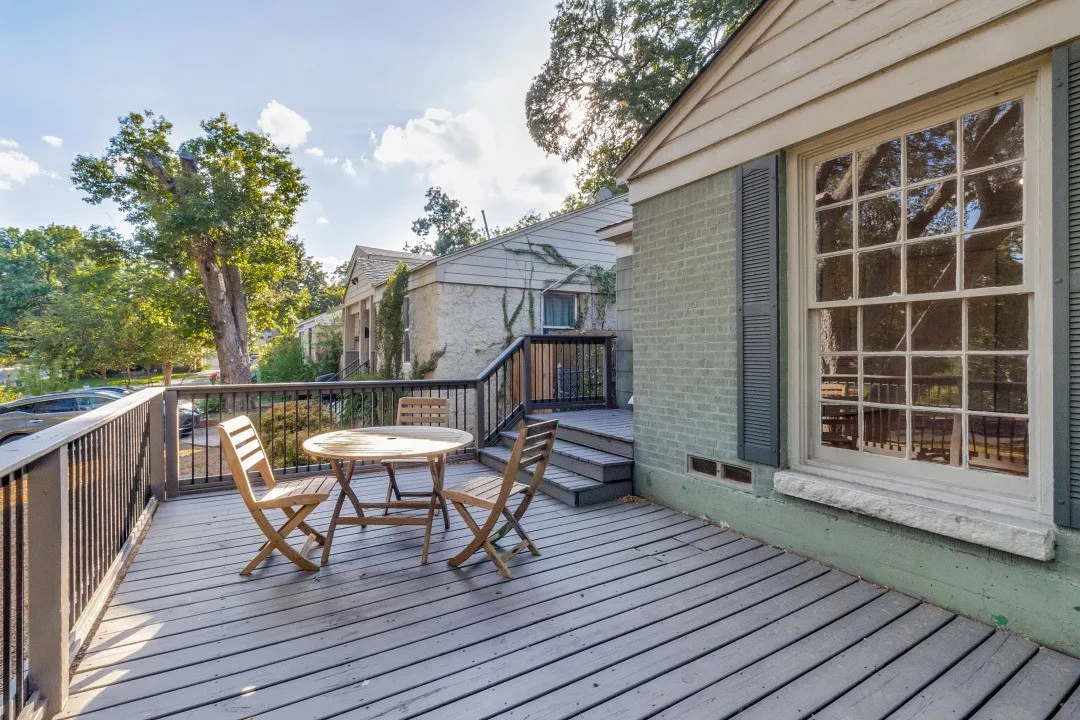 Expansive rear deck with dark railing, a multi-pane window, and painted brick siding