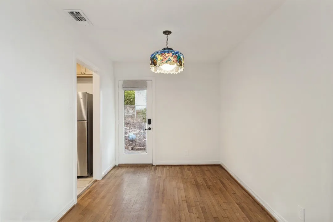 Hardwood flooring, painted white walls, ceiling-mounted light fixture, and a glass-paneled door