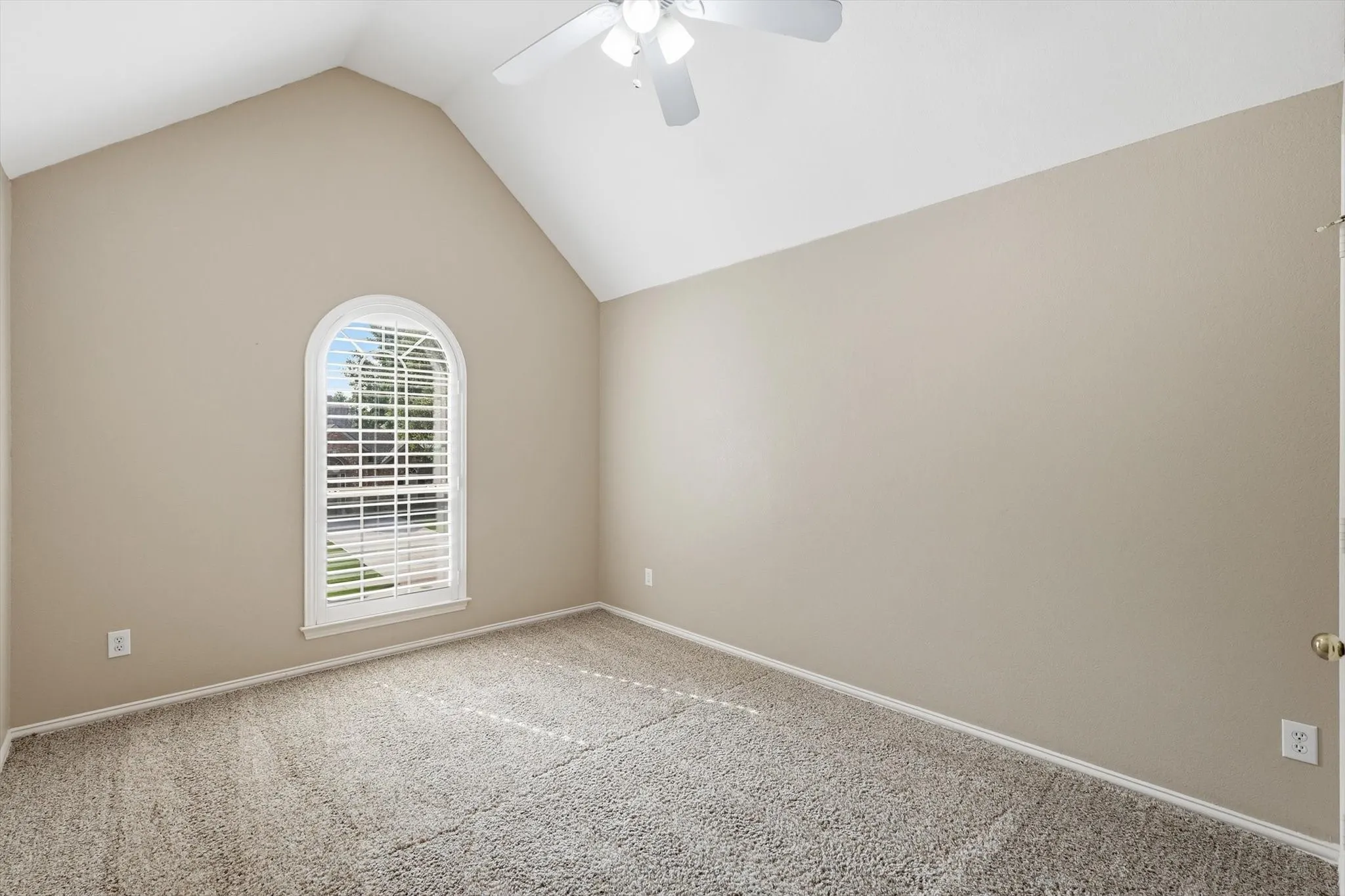 Upstairs Bedroom one with Vaulted ceiling room featuring plantation shutters, neutral tone walls, a ceiling fan