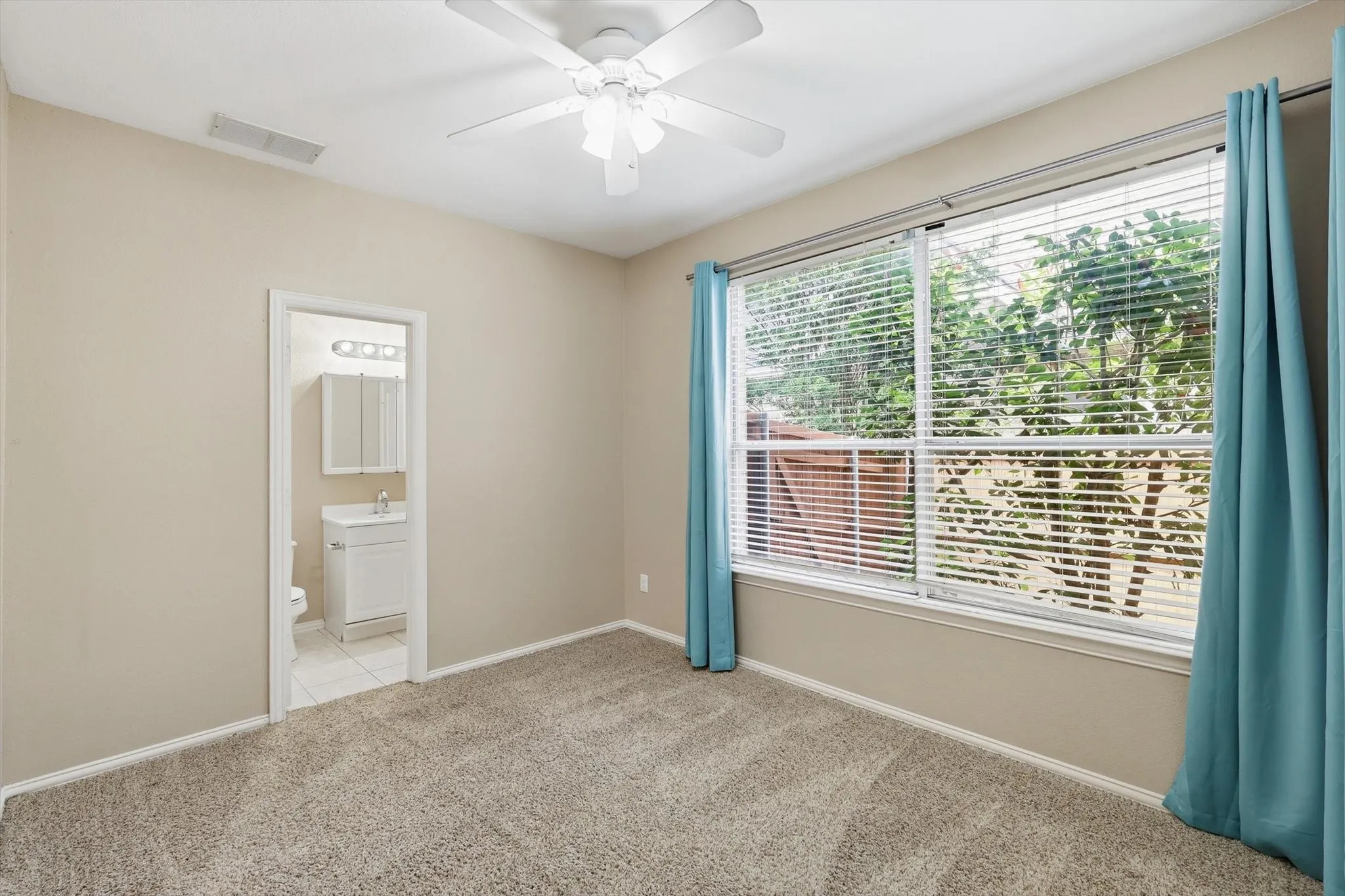 Guest Bedroom downstairs featuring a full attached bathroom, a ceiling fan, Large window looking out to backyard