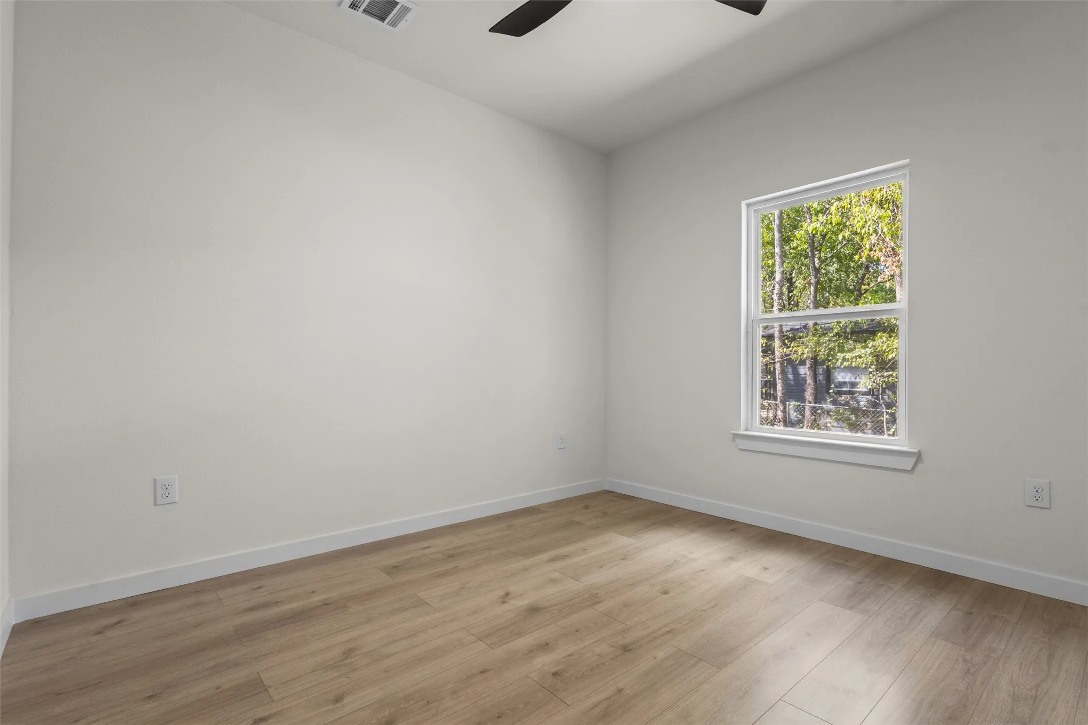Wood-finish flooring, white walls, and a single window with white trim