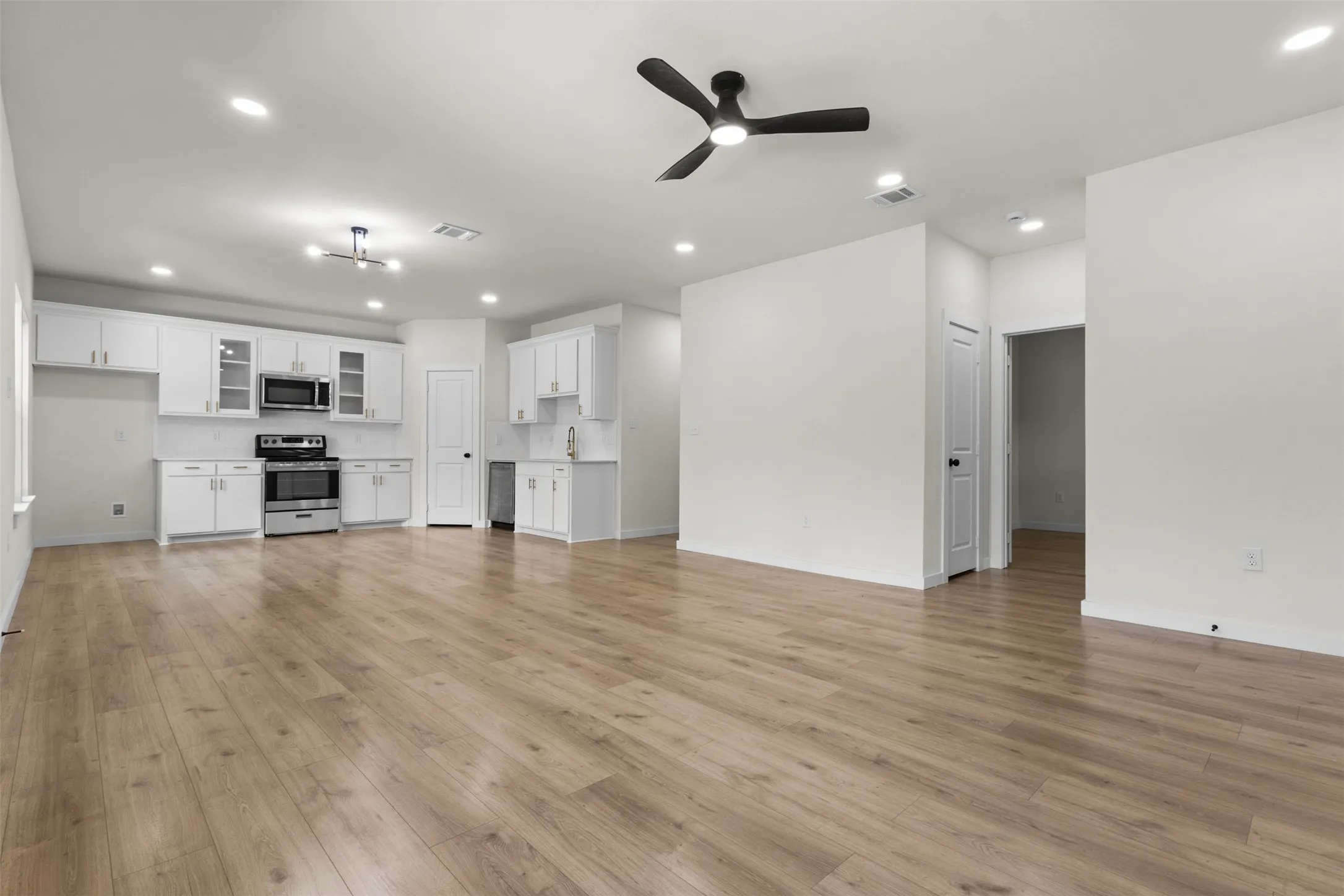 Open-concept living area featuring wood-finish flooring, recessed lighting, and a modern ceiling fan