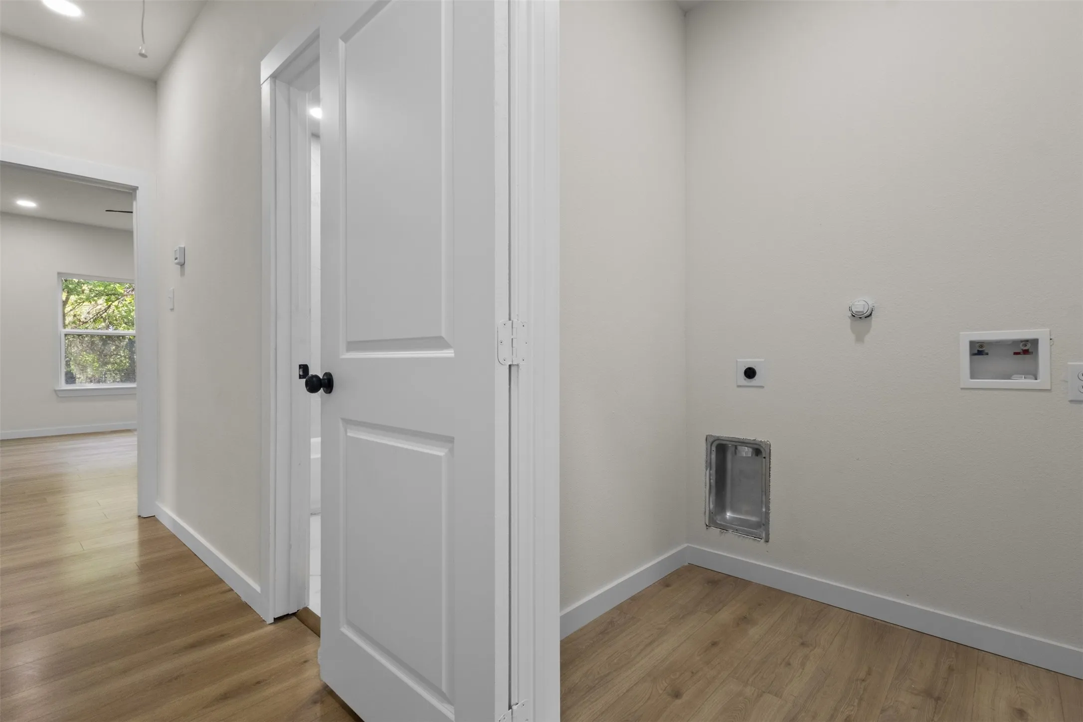 Dedicated laundry area with hookups, wood-finish flooring, and crisp white walls