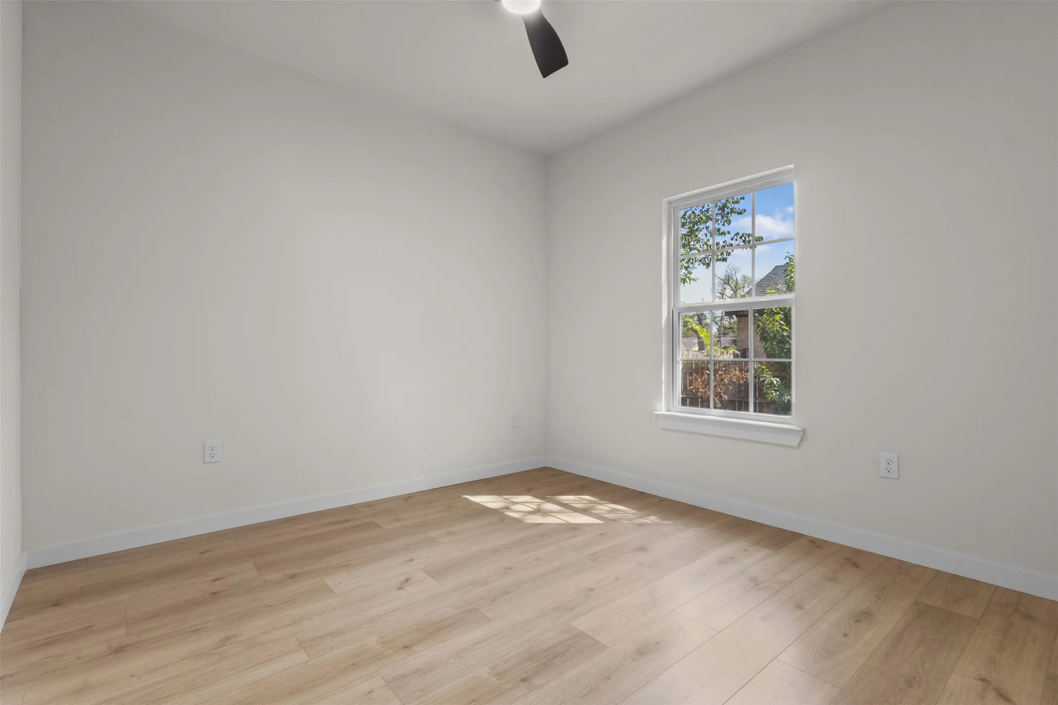 Wood-finish flooring, white walls, single window, and a ceiling fan