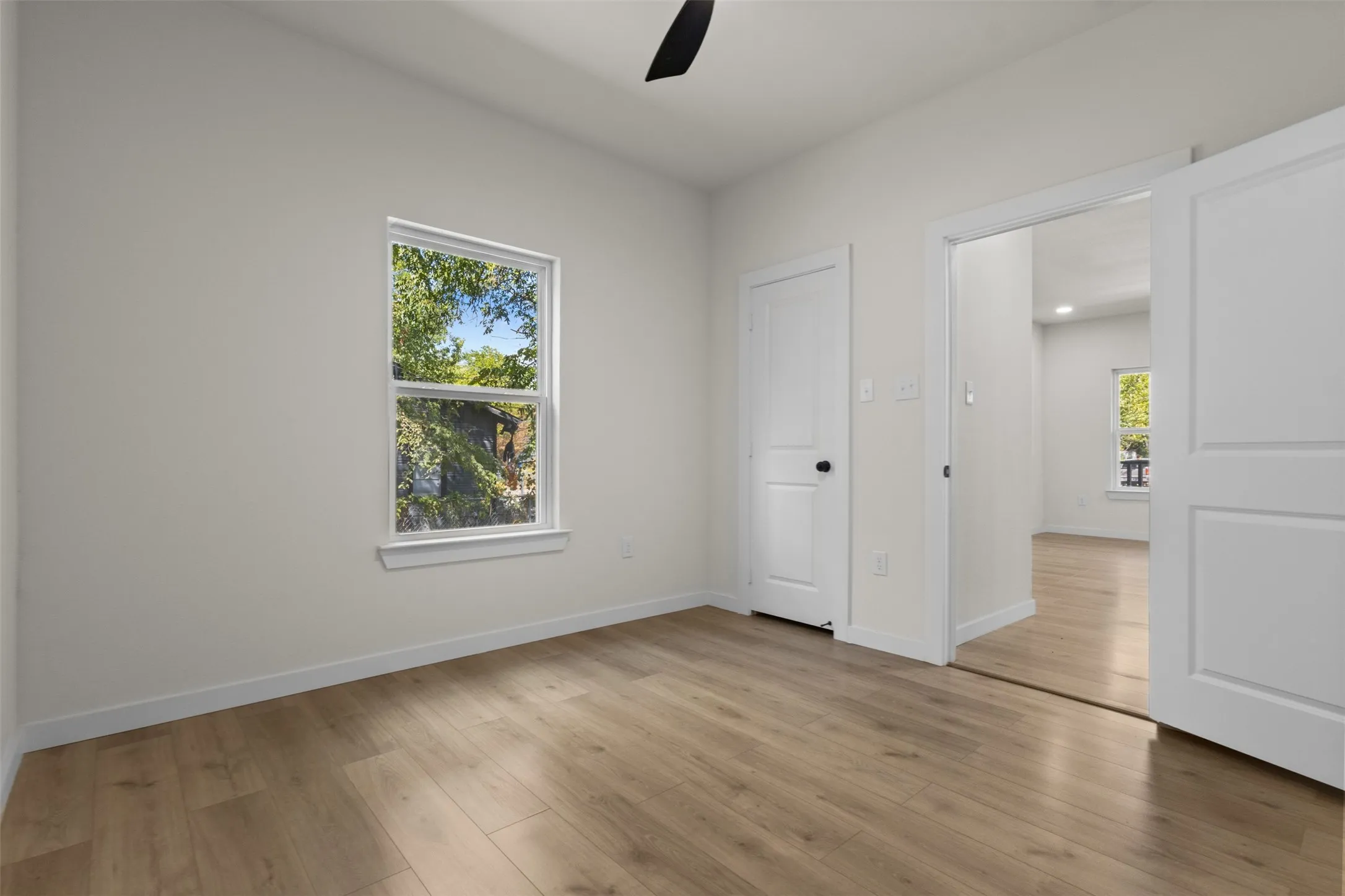 Light wood-finish flooring throughout, white walls, and a window with white trim