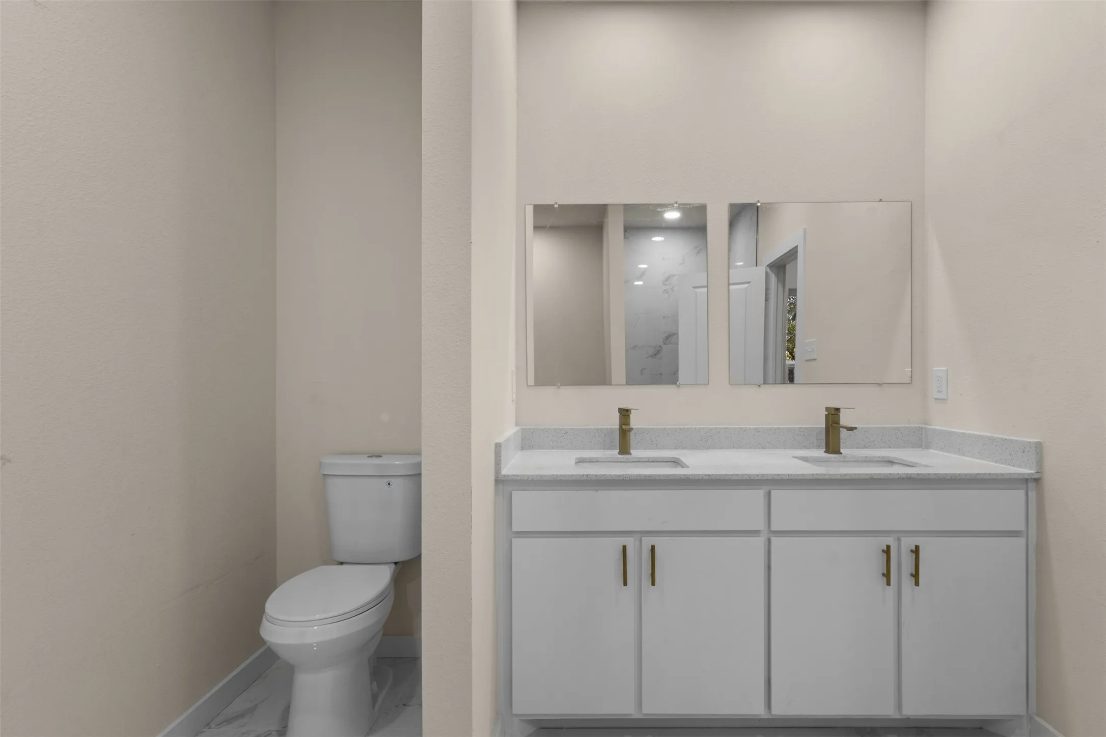 Dual vanity with light-toned countertop and gold-finish faucets