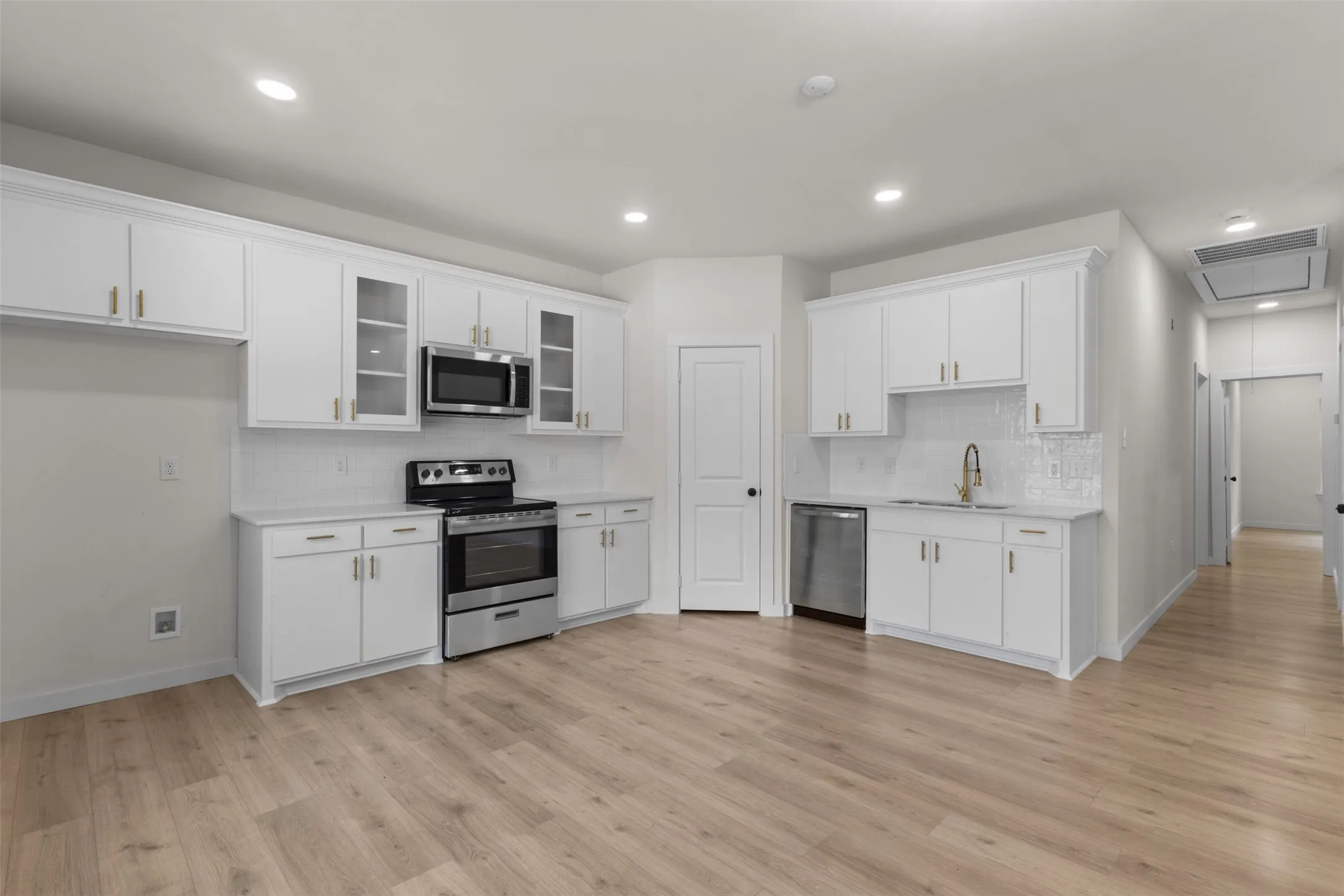 Kitchen featuring white cabinetry, stainless steel appliances, wood-finish flooring, recessed lighting, and a subway tile backsplash