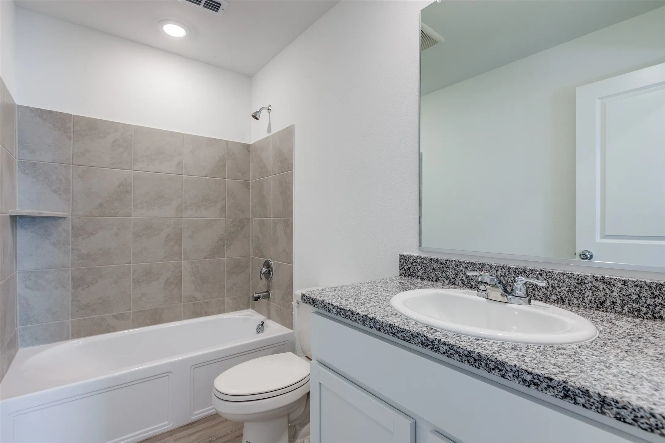 Full bathroom featuring vanity, hardwood / wood-style floors, tiled shower / bath combo, and toilet
