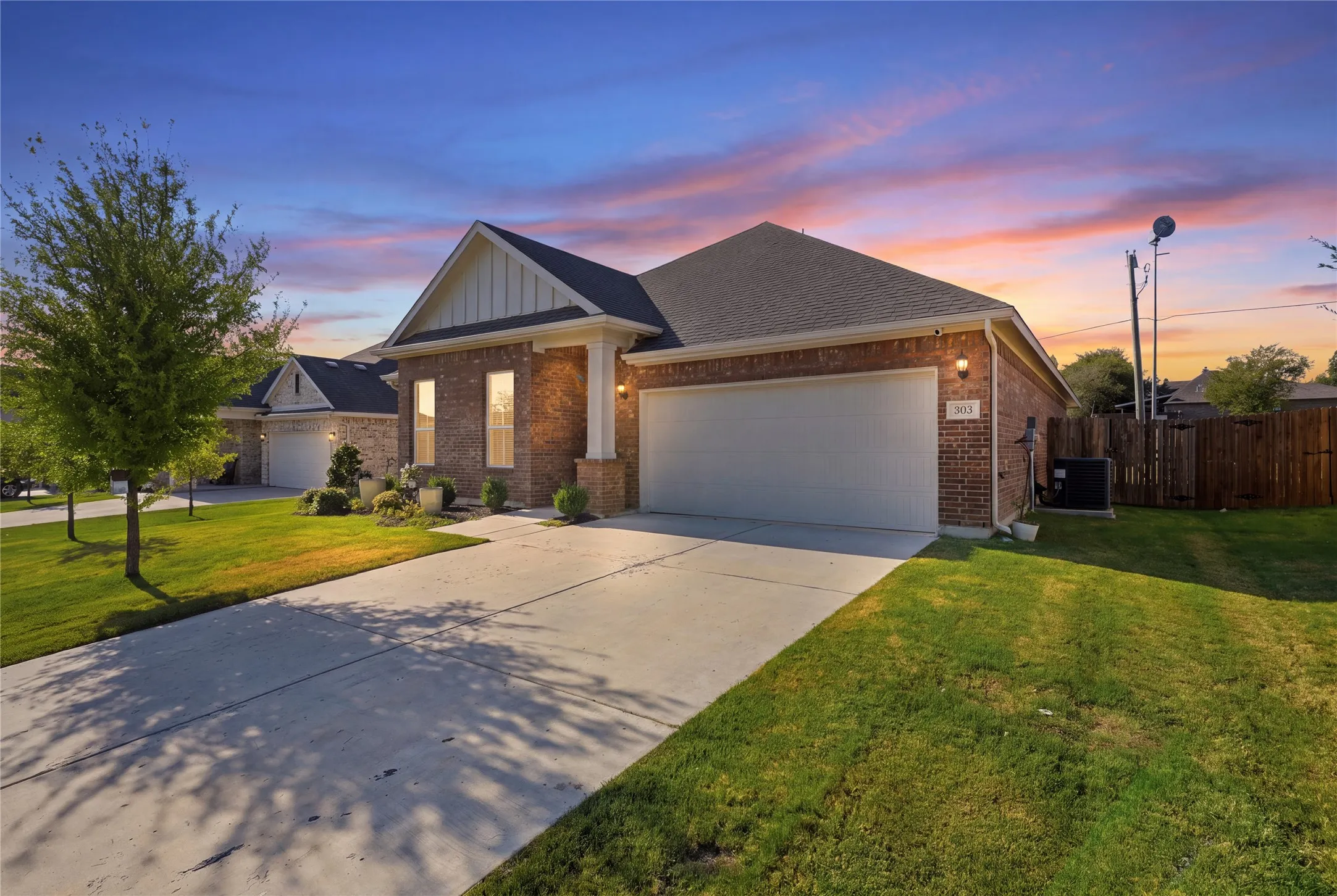 Brick exterior with a gabled roofline, concrete driveway, and attached garage