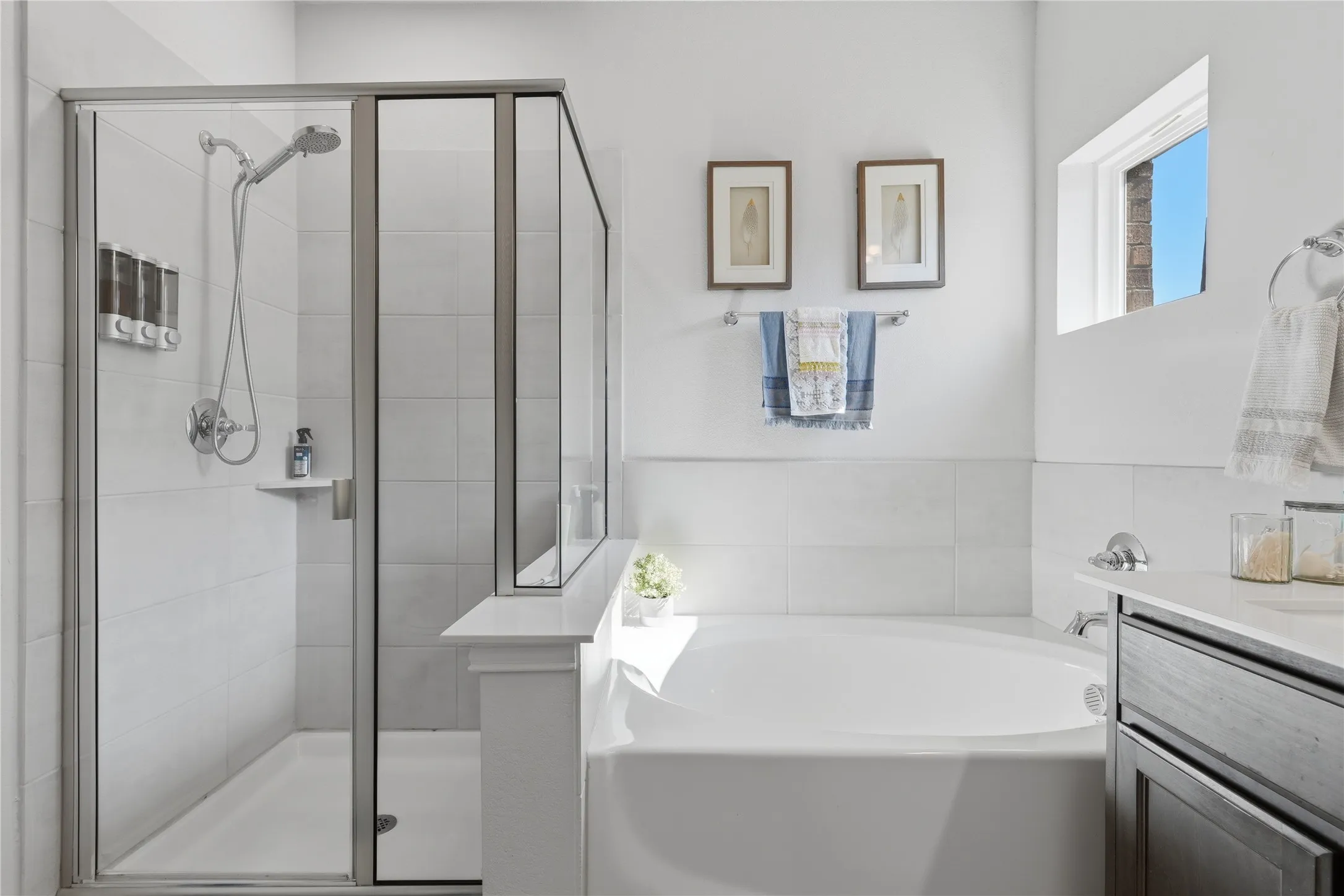 Glass-enclosed shower with a handheld showerhead, built-in shower niche, and white tiled walls